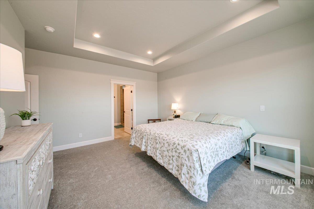 Bedroom with a tray ceiling, light colored carpet, and recessed lighting
