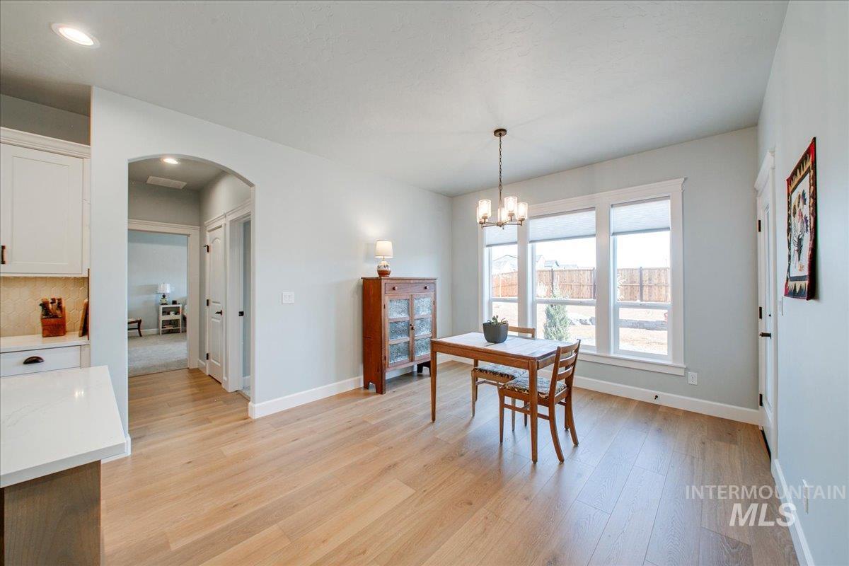 Dining room featuring arched walkways, light wood finished floors, and a chandelier