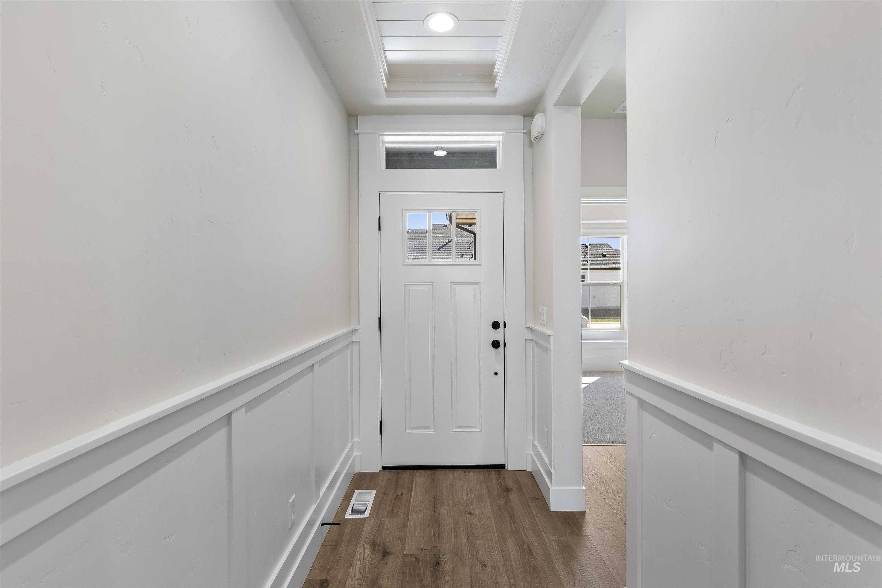 Entryway featuring wainscoting, wood finished floors, and a decorative wall