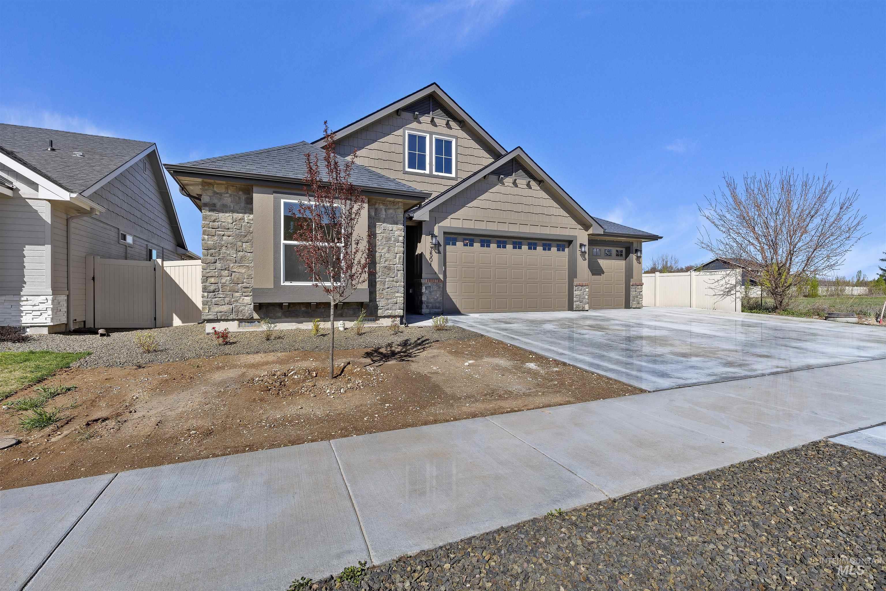 Craftsman house featuring stone siding, concrete driveway, an attached garage, and a gate