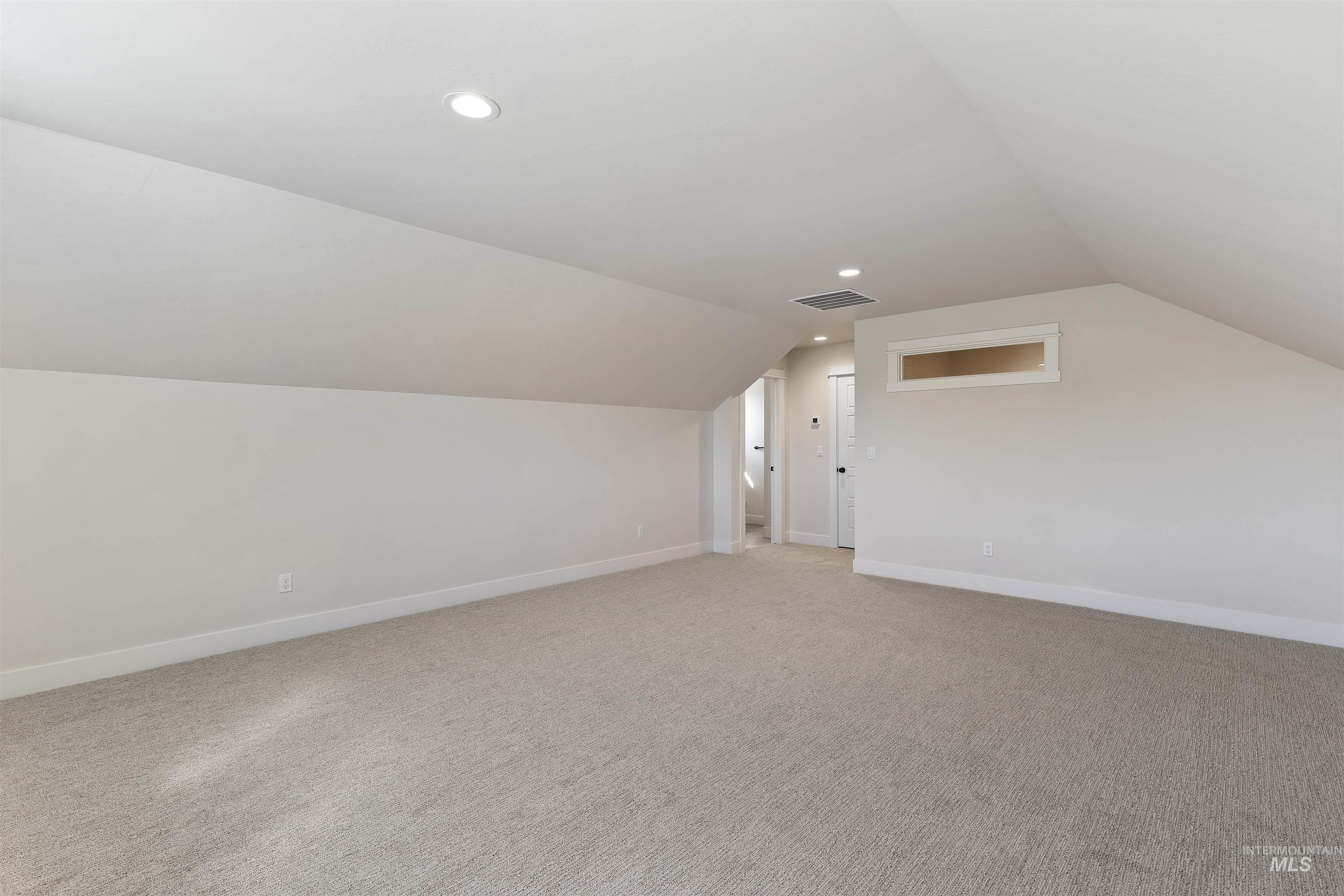 Bonus room with light colored carpet and recessed lighting