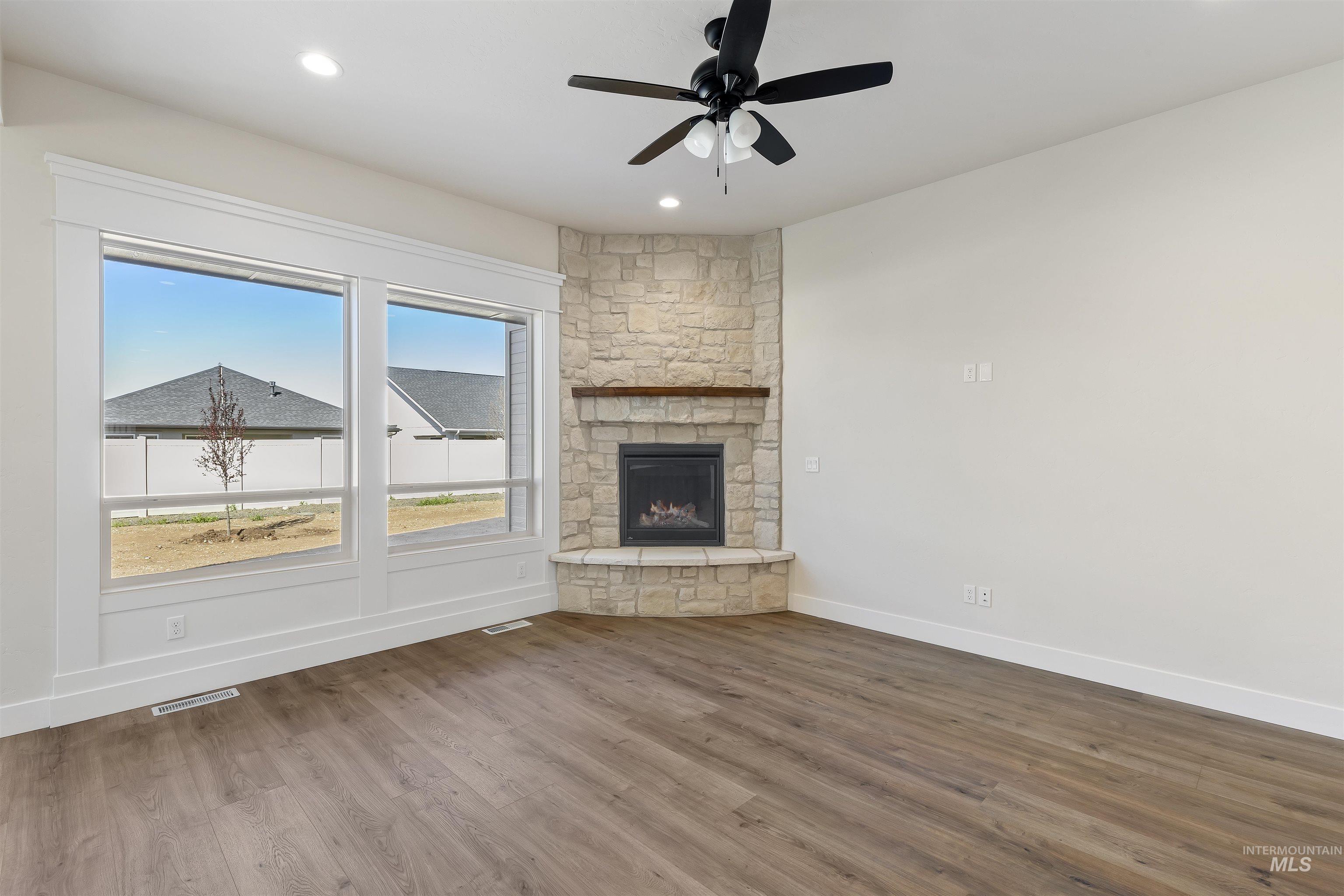 Unfurnished living room with a ceiling fan, dark wood-style floors, recessed lighting, and a fireplace
