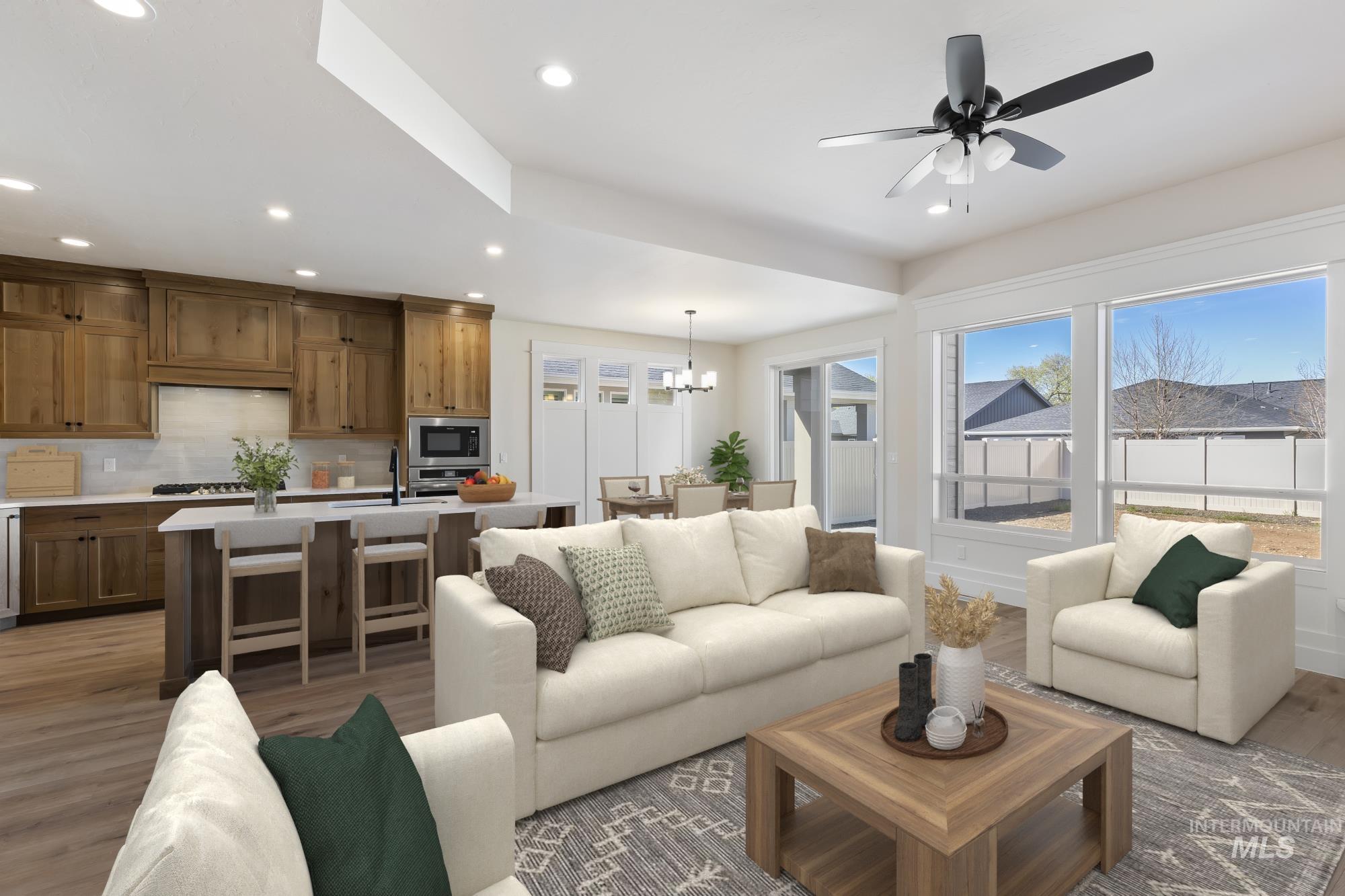 Living room featuring light wood-style flooring, a ceiling fan, and suspended lighting