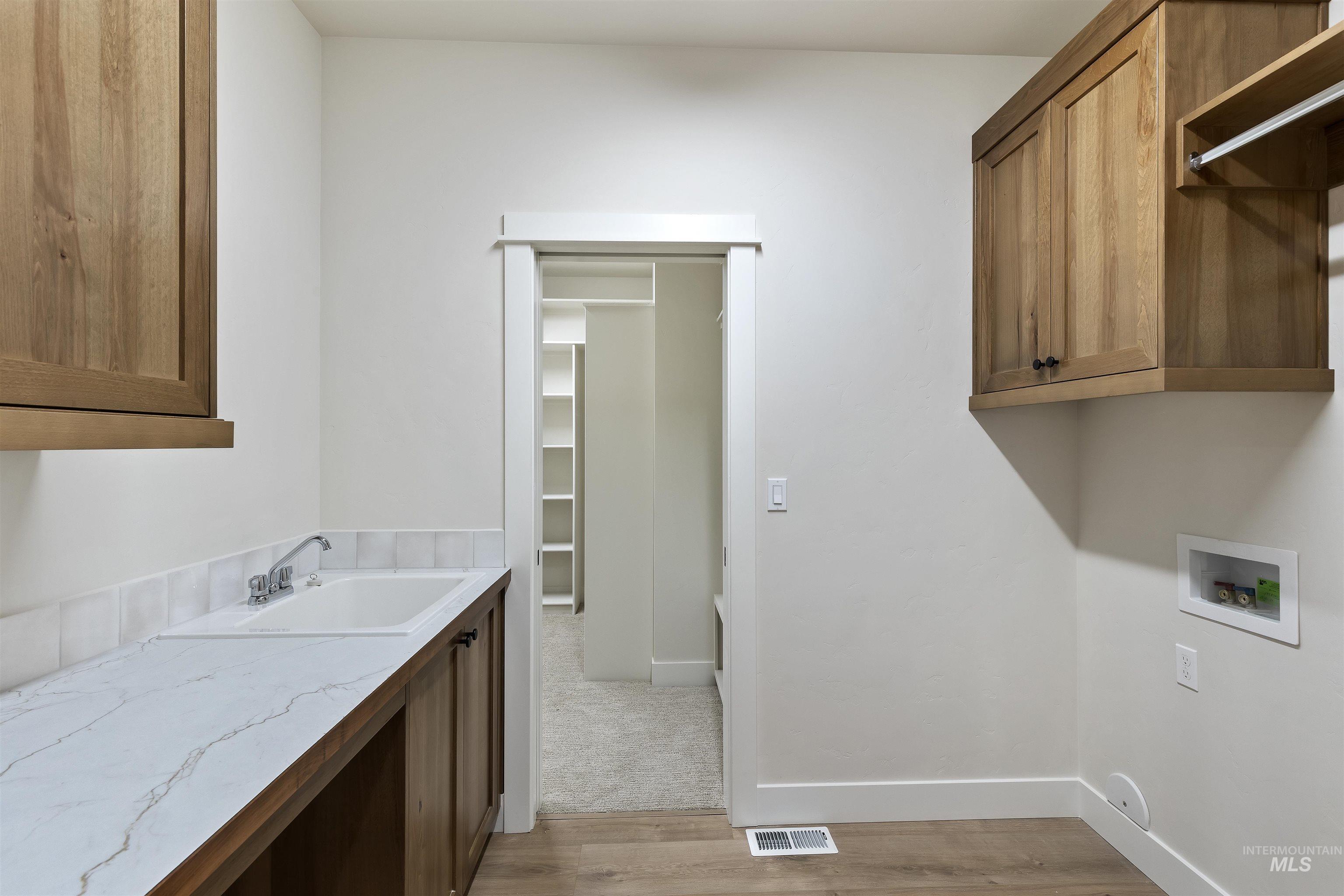 Laundry area with cabinet space, light wood-style flooring, and washer hookup
