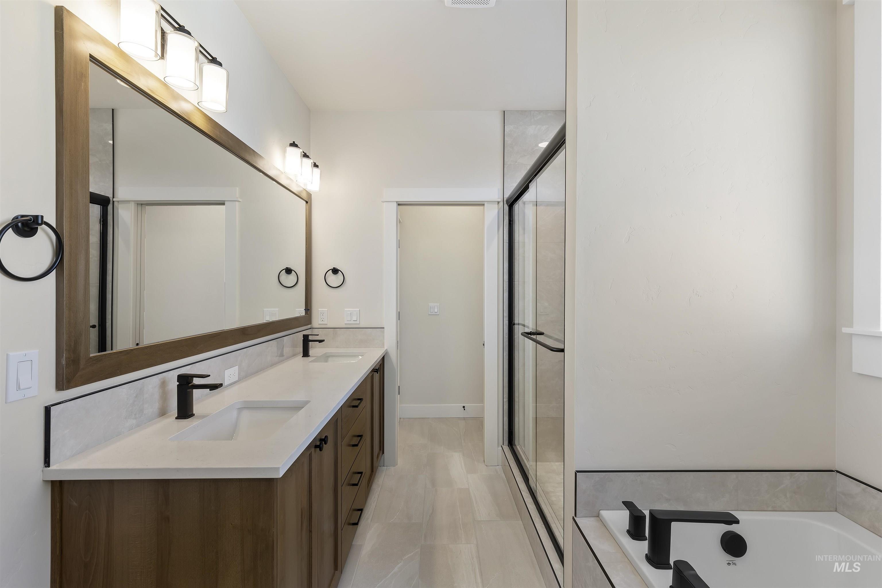 Bathroom with double vanity, a bath, and a shower stall