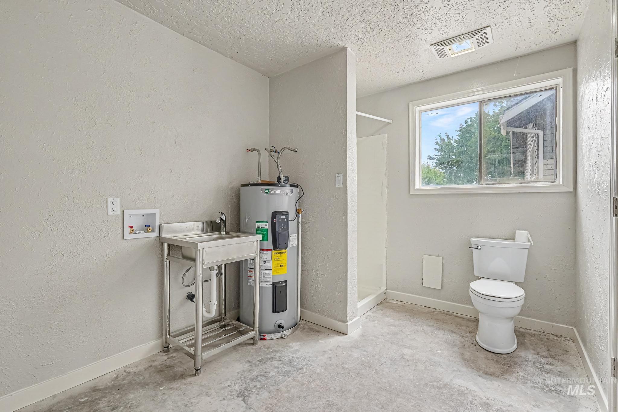 Utility room with a built-in shower, toilet, and stainless steel utility sink with storage