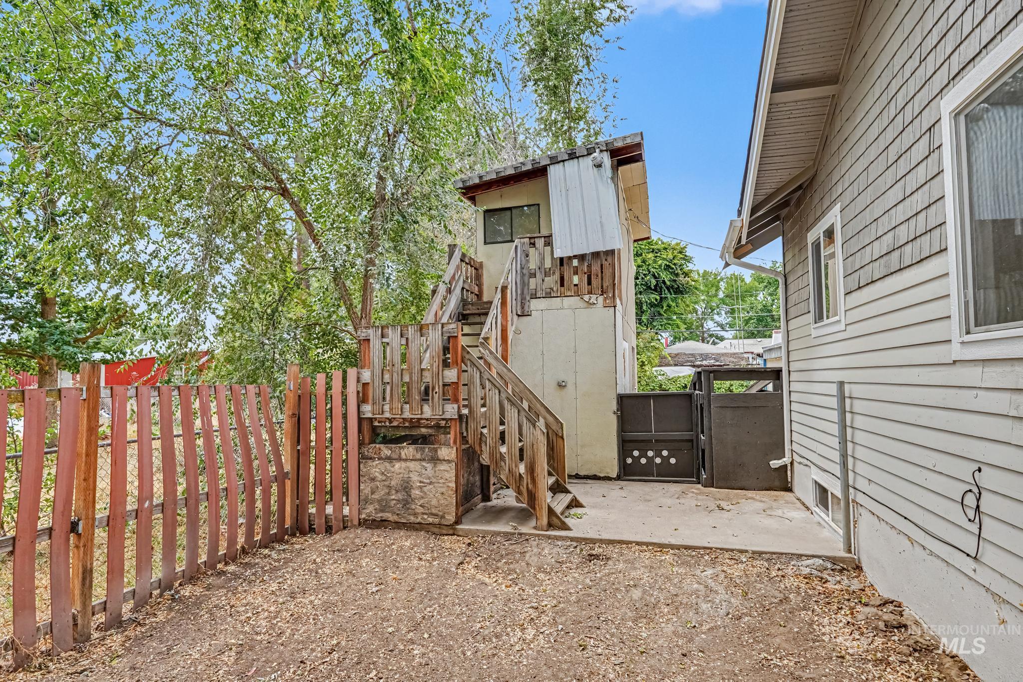Rear exterior featuring a multi-level wooden deck with stairs, a concrete patio area, and a privacy fence