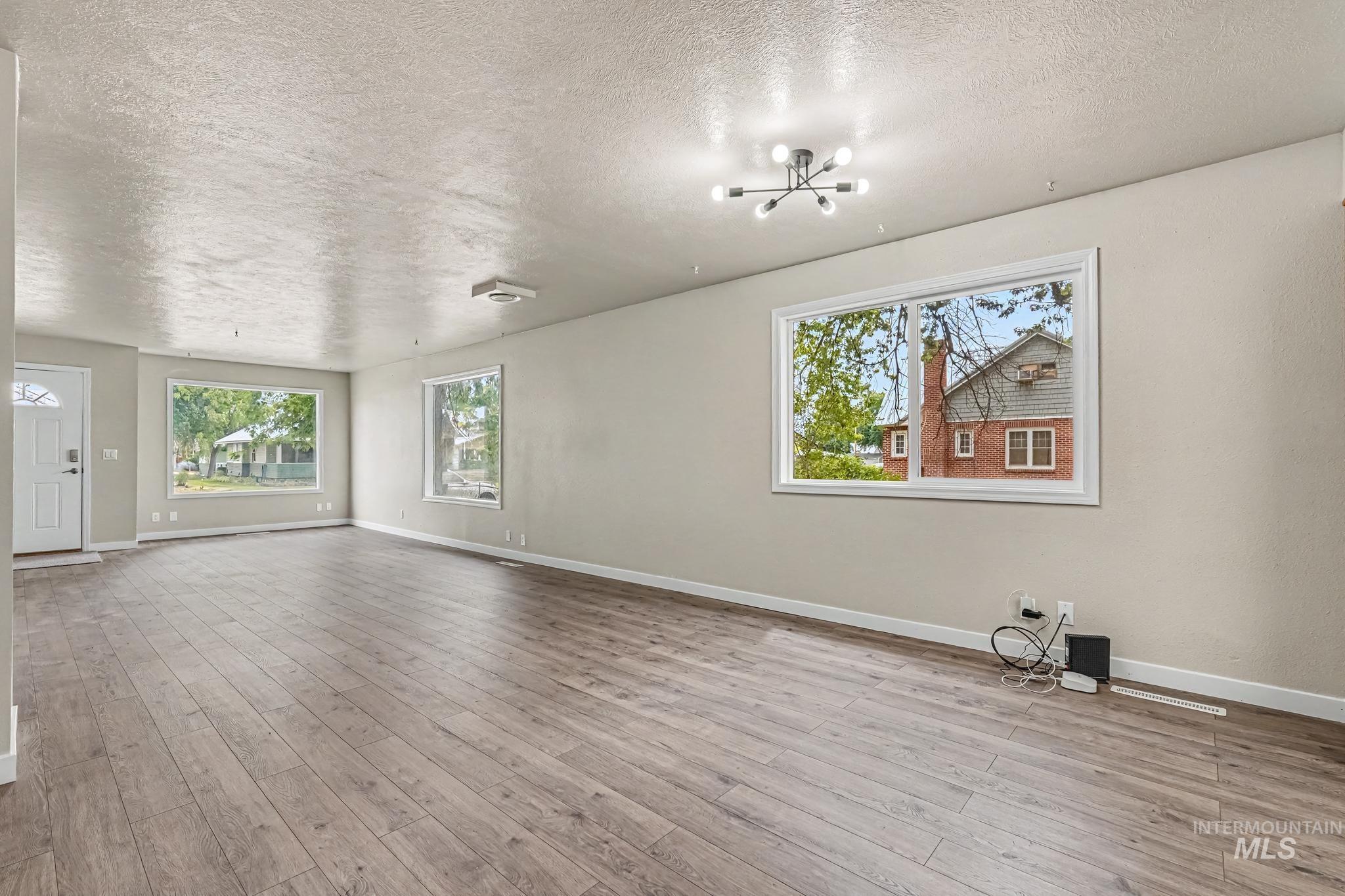 Spacious room featuring wood-finish flooring, light neutral wall paint, and multiple windows with white trim