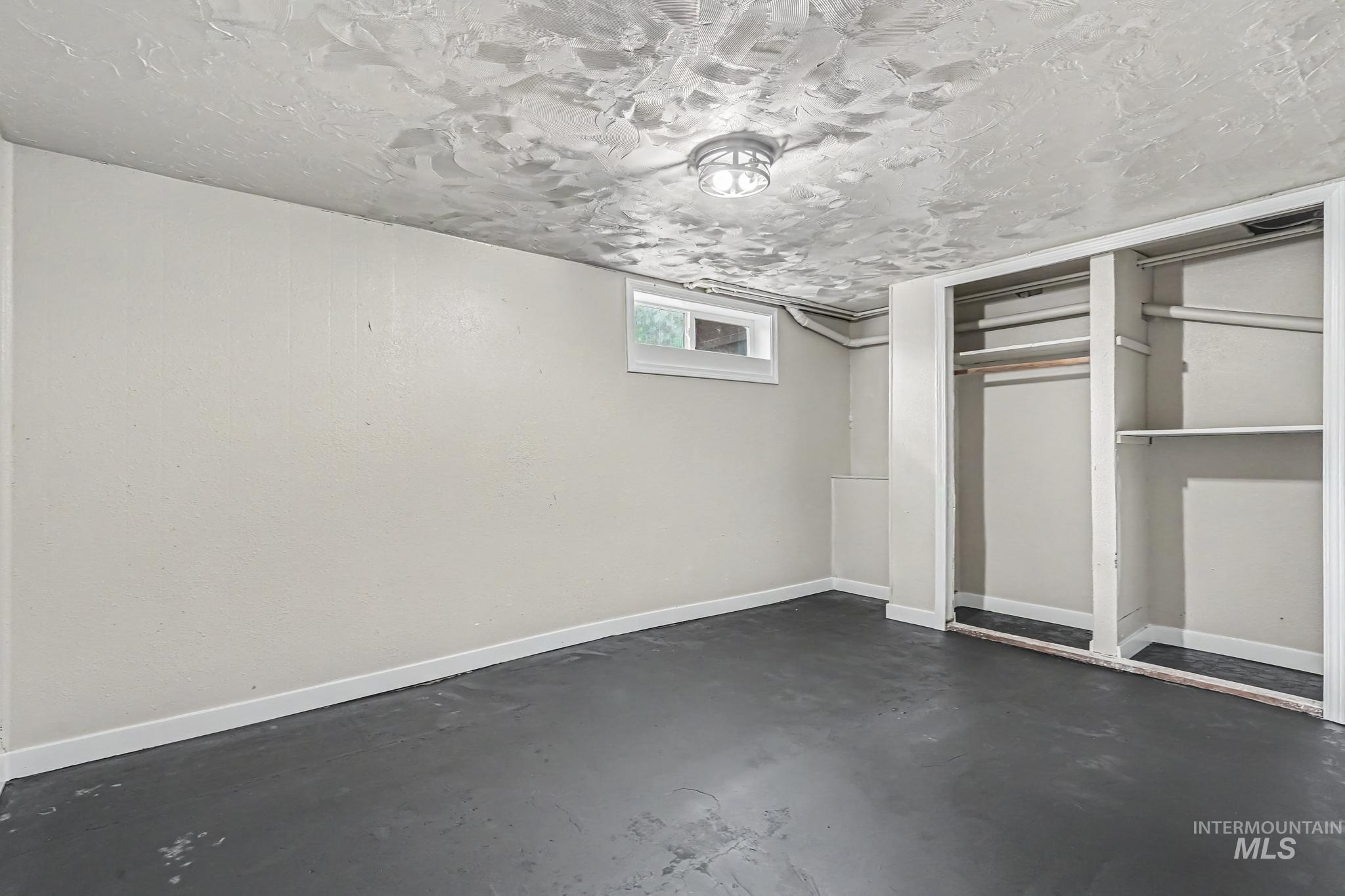 Finished room featuring painted concrete flooring and light-toned walls