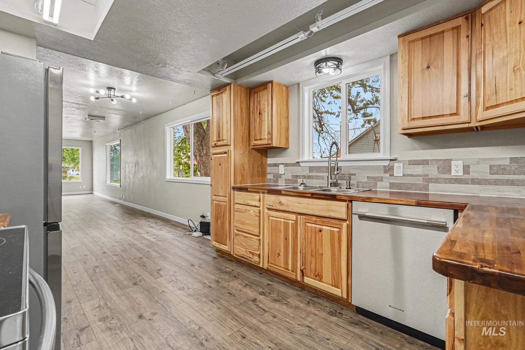Kitchen featuring natural wood cabinetry, wood-finish countertops, stainless-steel appliances, and a mosaic tile backsplash