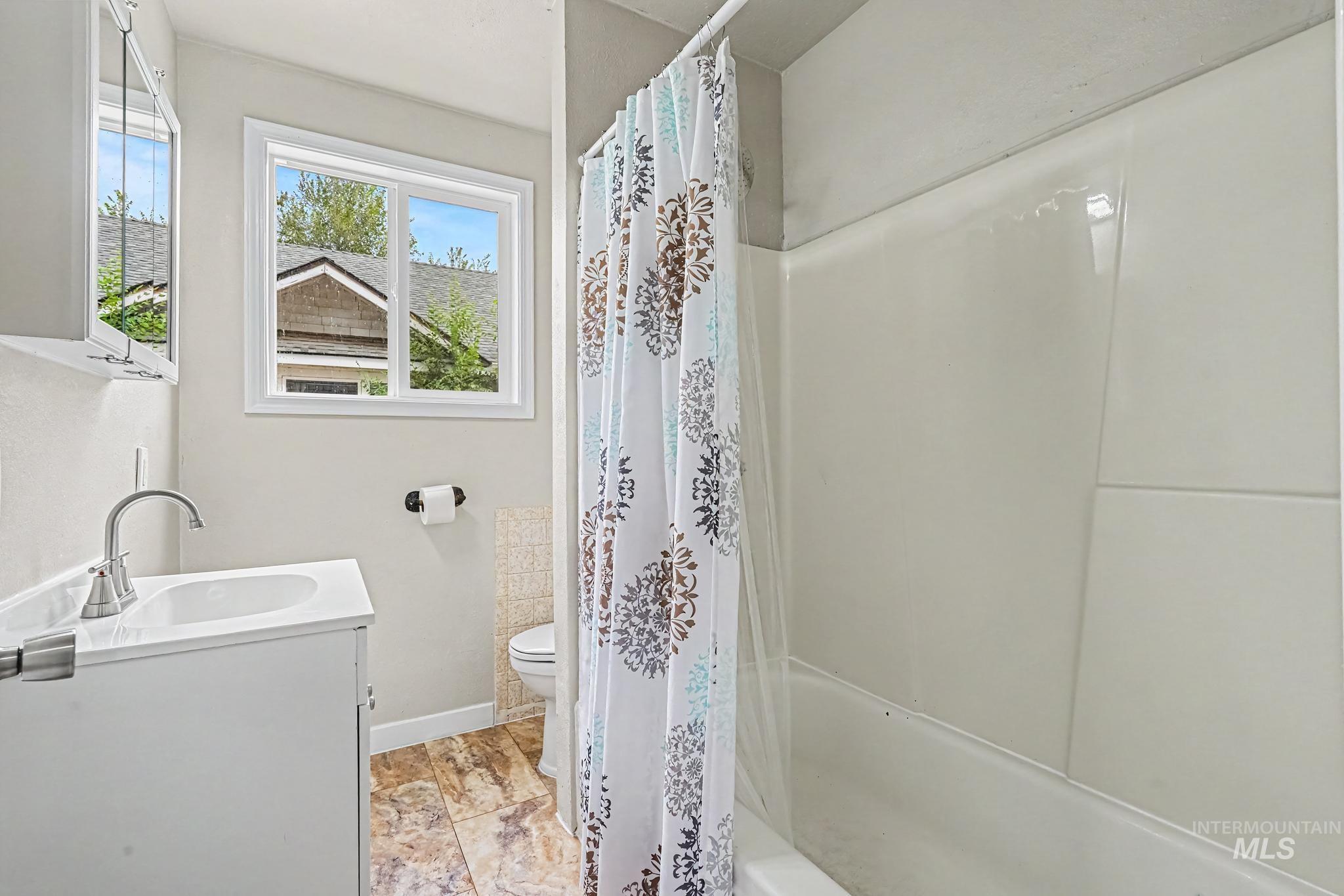 Bathroom featuring a single vanity with a white cabinet, a white sink, and a chrome faucet