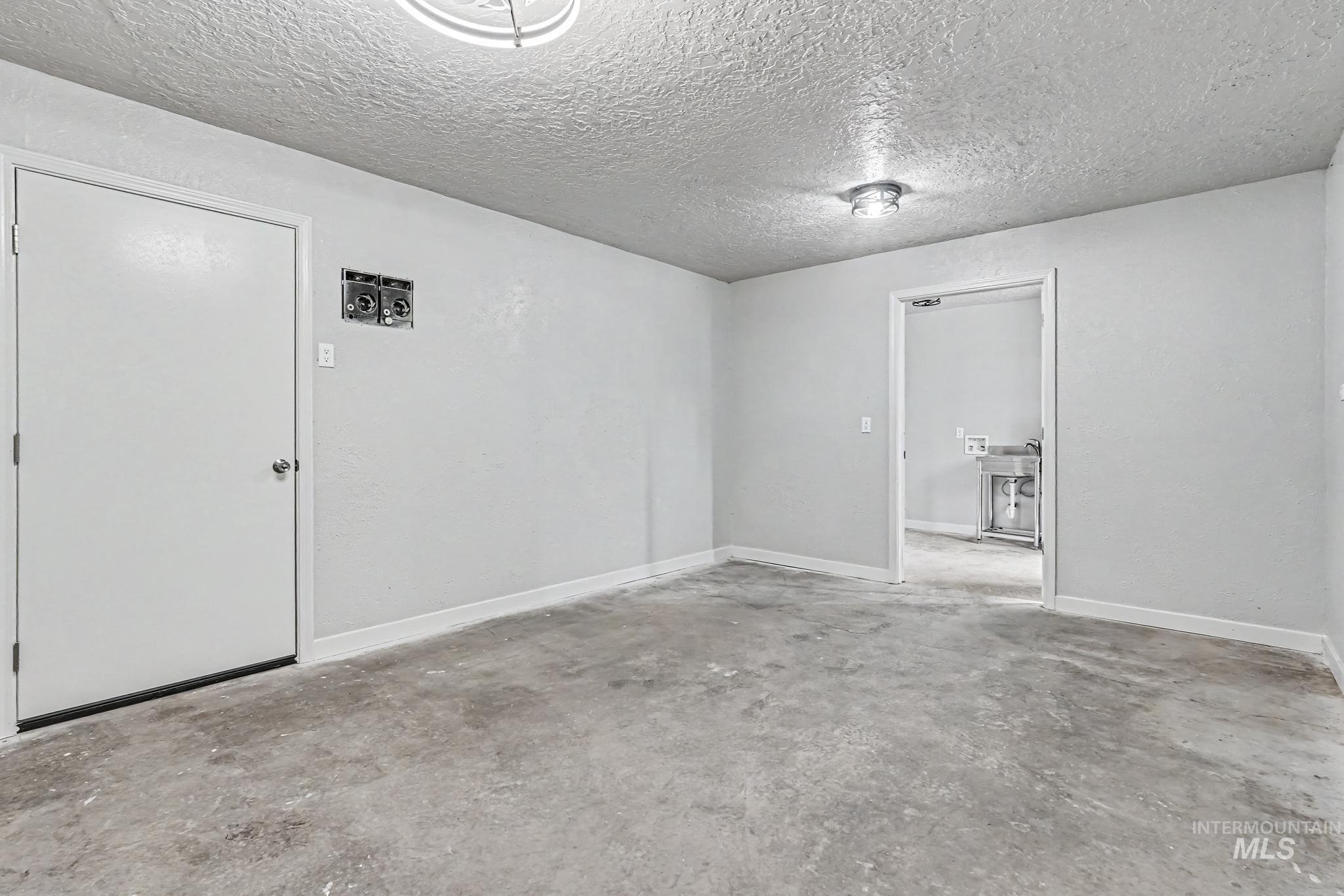 Spacious room with concrete flooring, light gray walls, and white trim