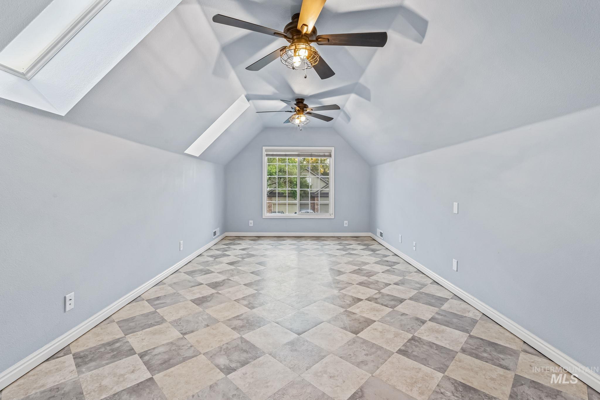 Bonus room featuring vaulted ceiling, two skylights, and ceiling fan