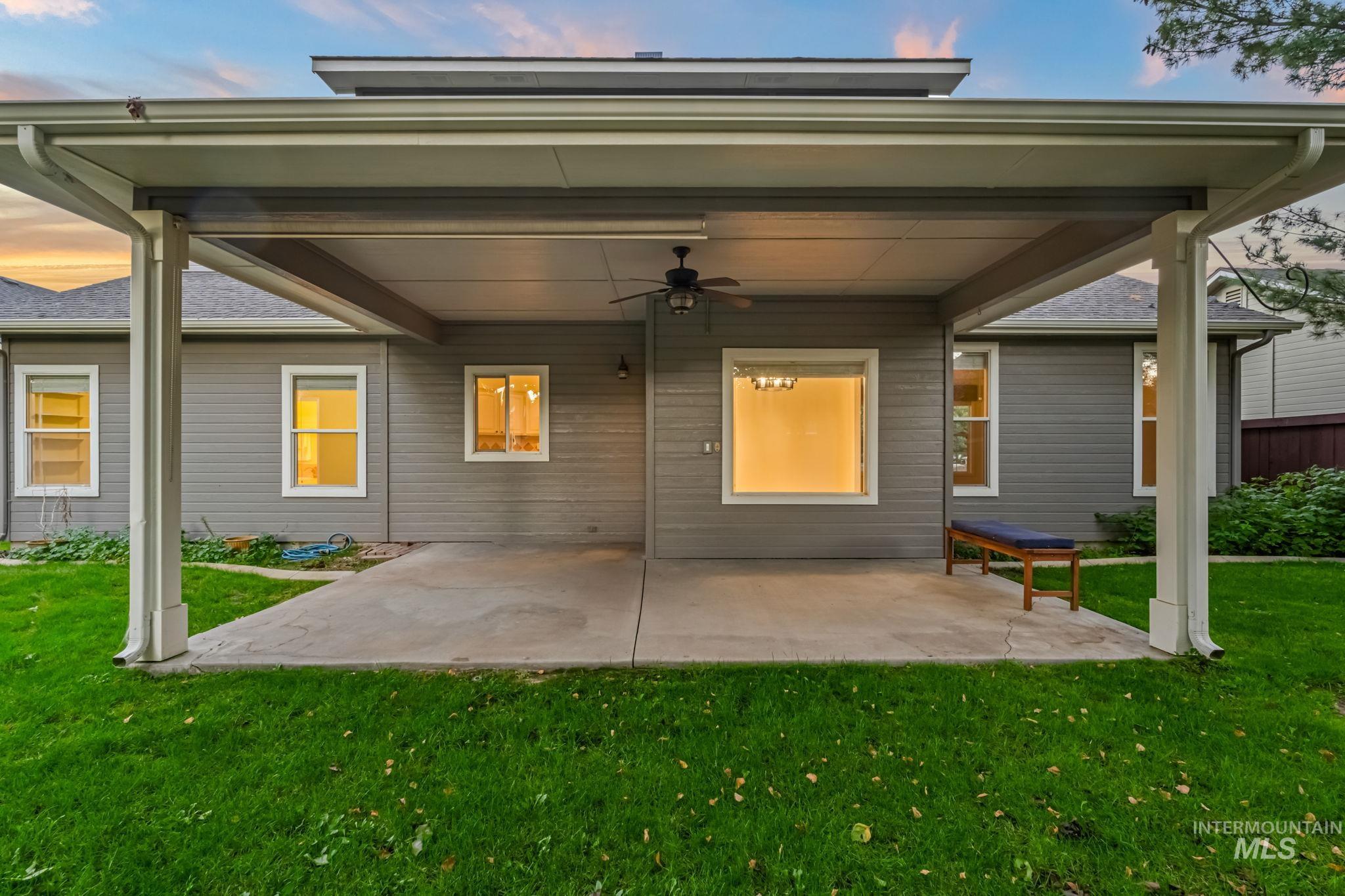 Rear view of house with a ceiling fan, a patio area, and a yard
