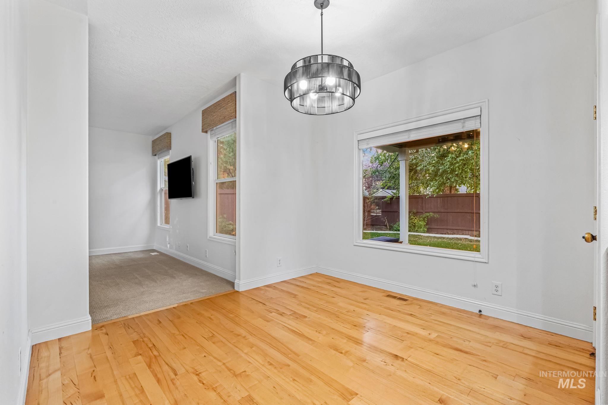 Unfurnished dining area featuring a chandelier, light wood-type flooring, and plenty of natural light