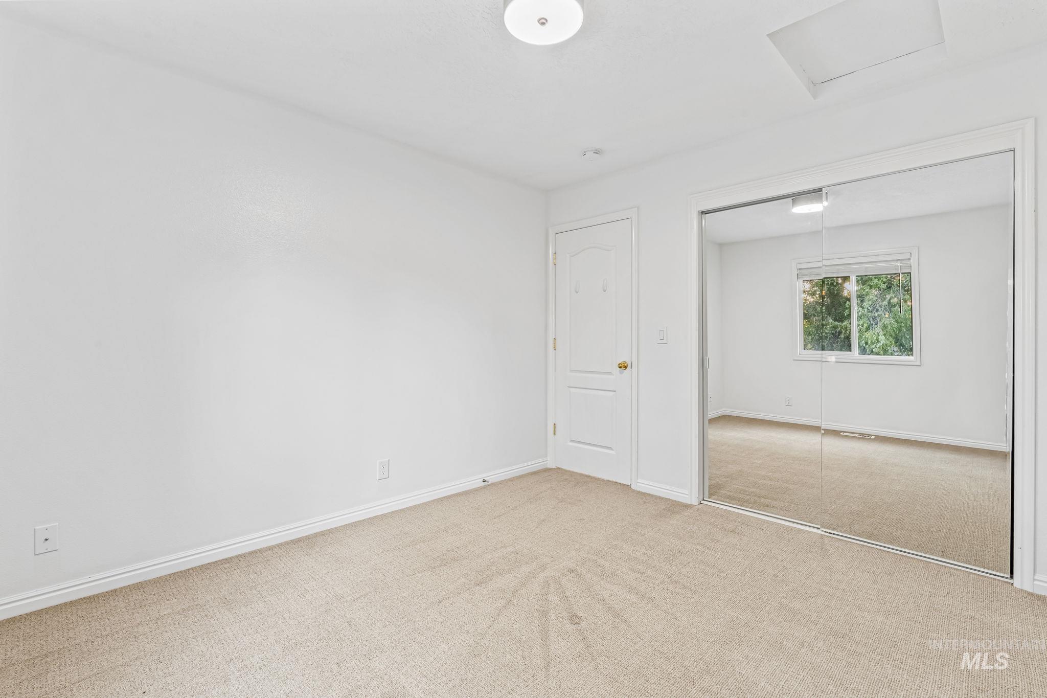 Unfurnished bedroom with carpet flooring, attic access, and a closet