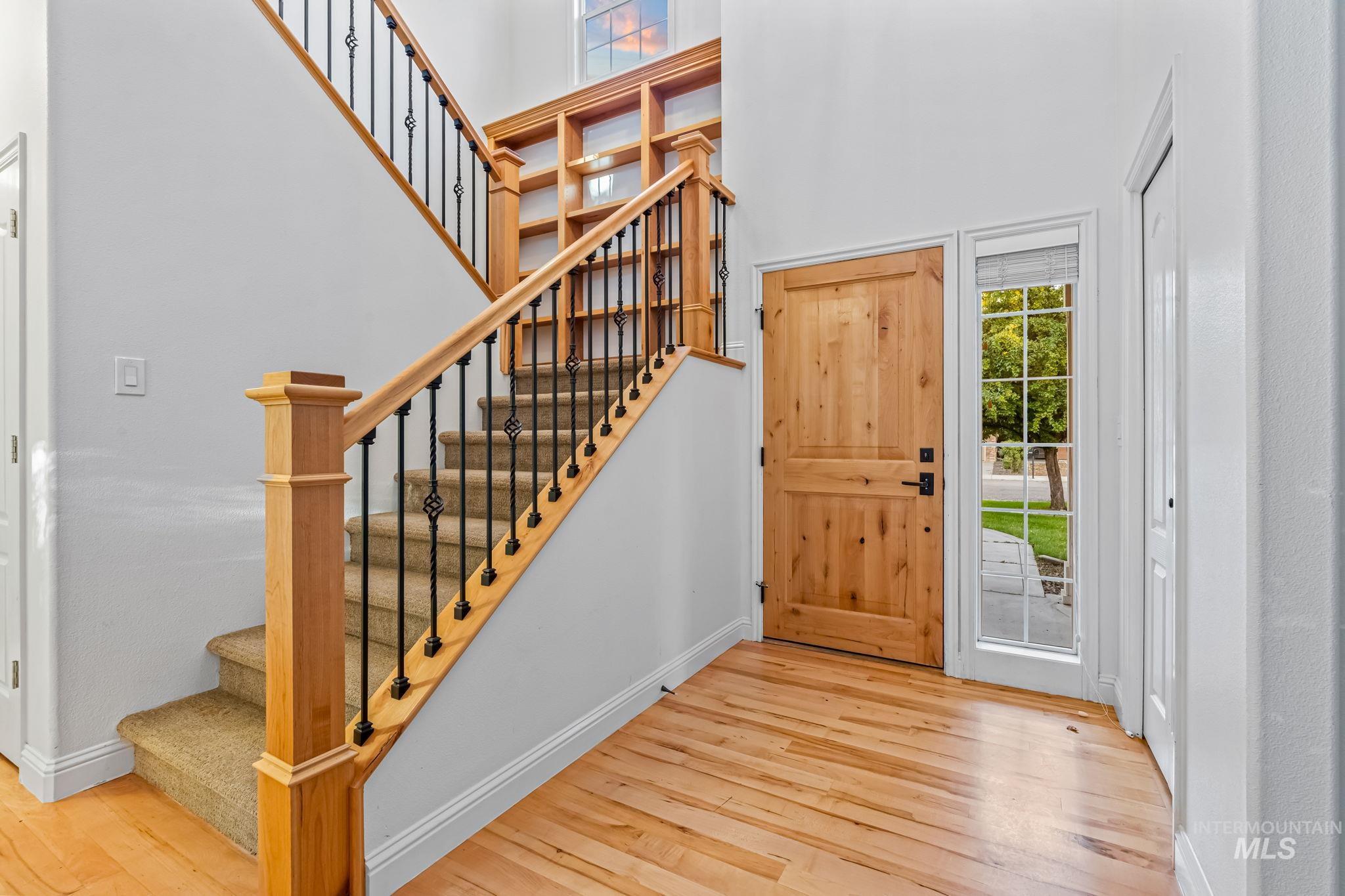 Foyer entrance featuring light wood-style flooring, stairs, and a towering ceiling
