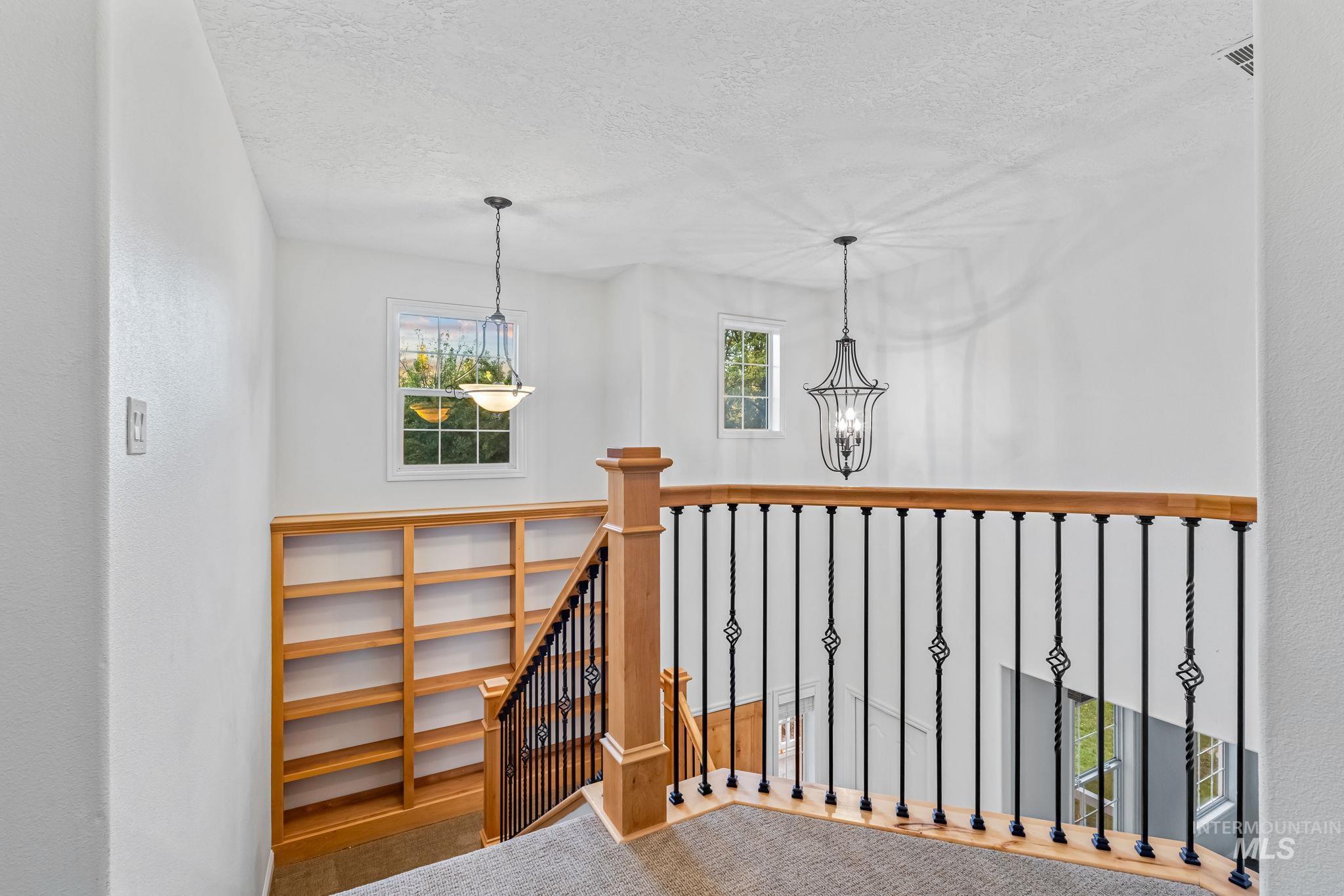 Staircase featuring a textured ceiling and a chandelier