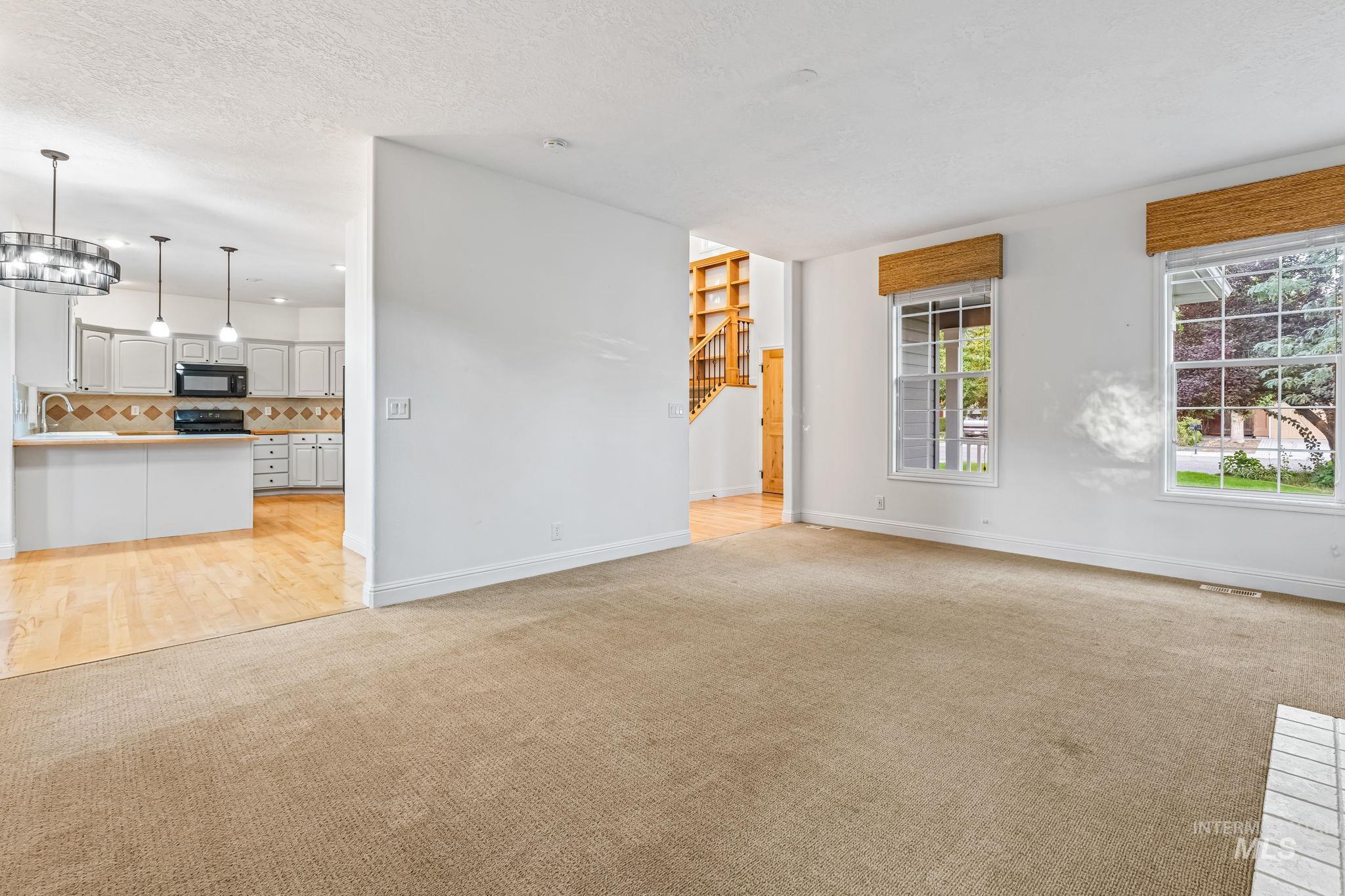 Unfurnished living room with light colored carpet, a textured ceiling, and light wood finished floors