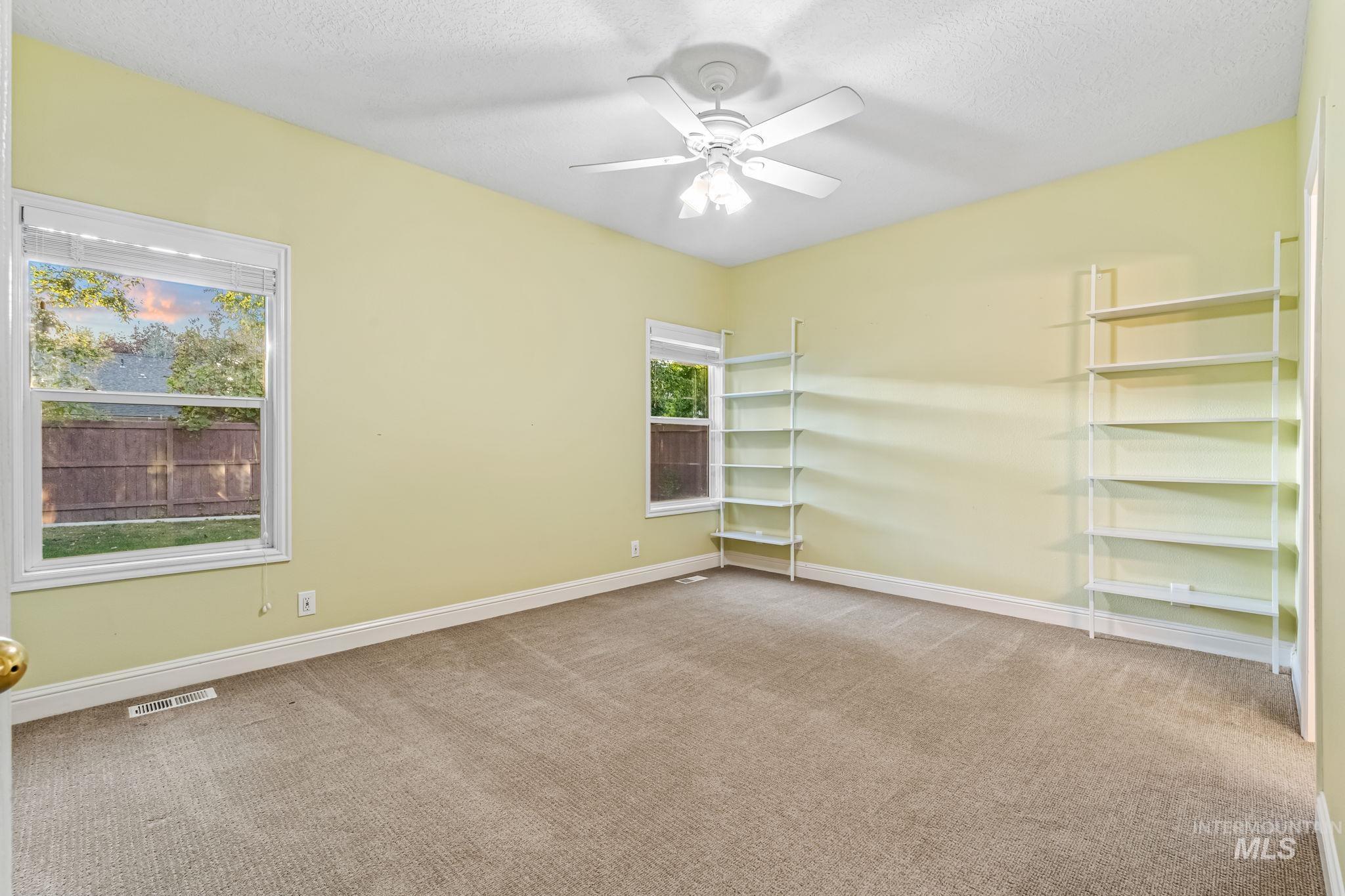 Spare room featuring light colored carpet, a ceiling fan, and a textured ceiling