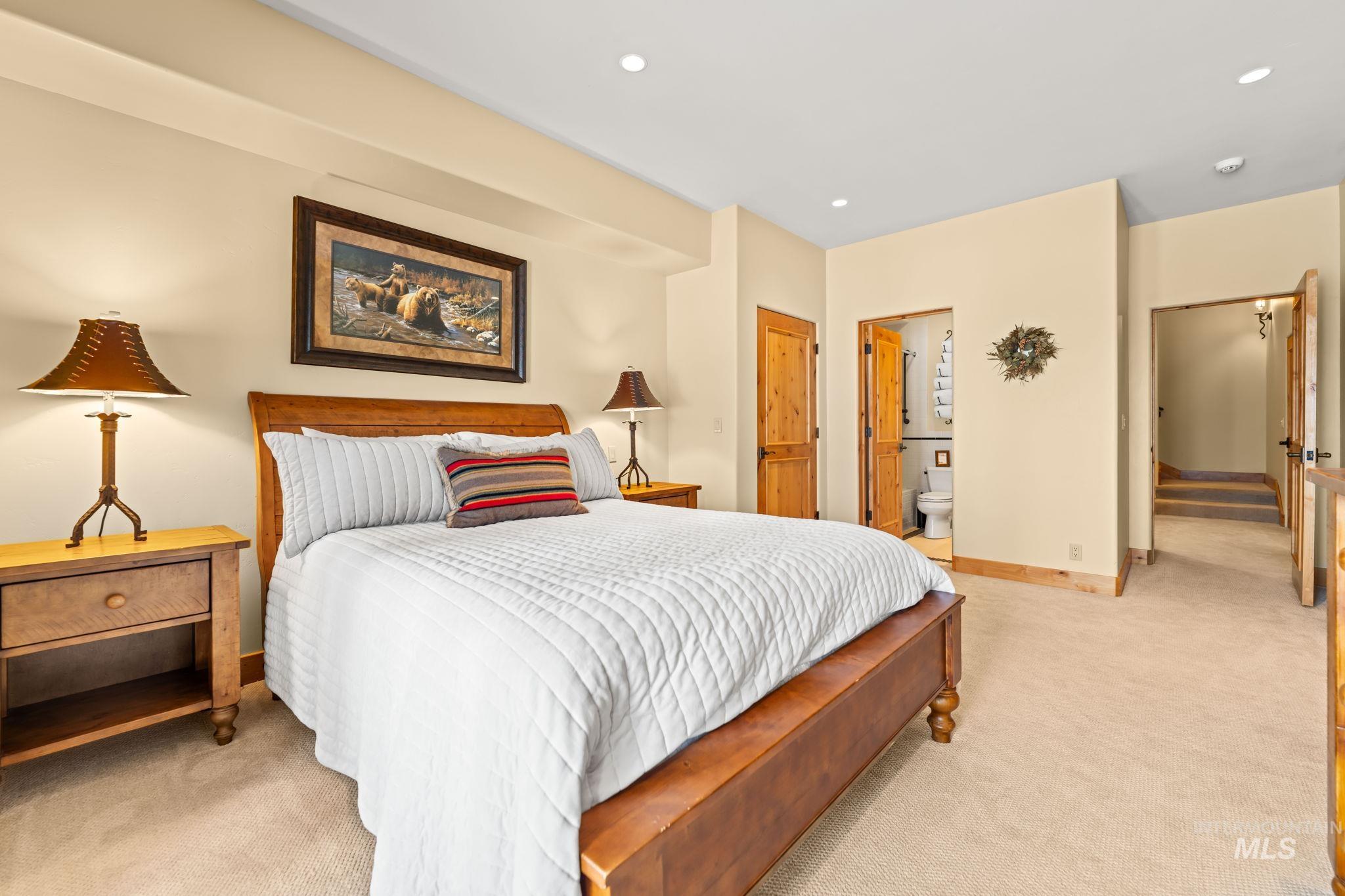 Bedroom featuring light colored carpet, ensuite bath, and recessed lighting