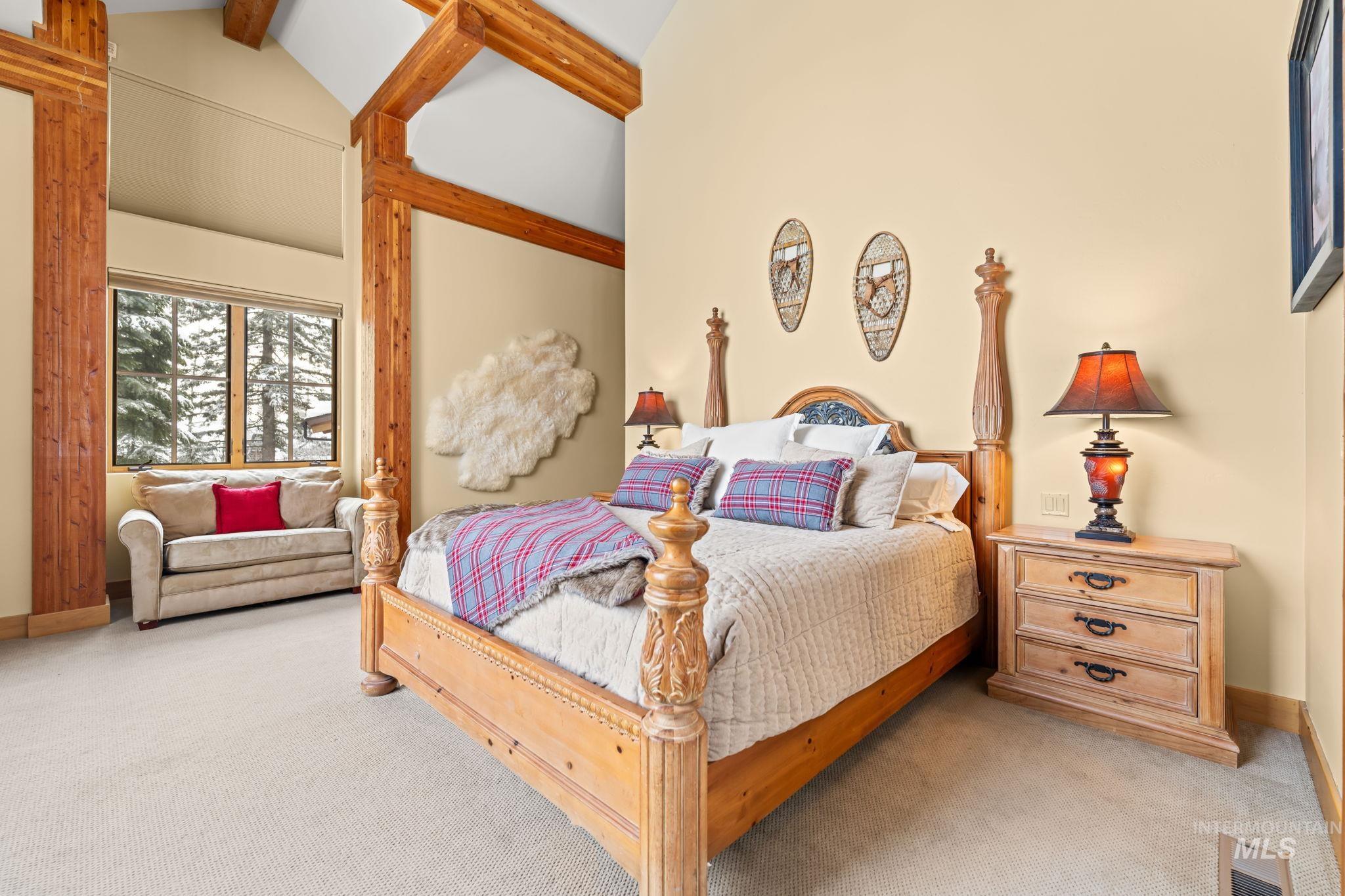 Carpeted bedroom with beam ceiling and high vaulted ceiling