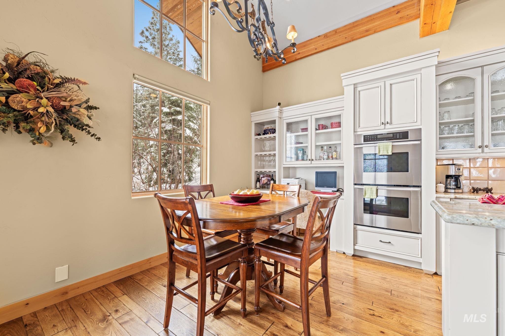 Dining area with a high ceiling, light wood-style flooring, and a chandelier