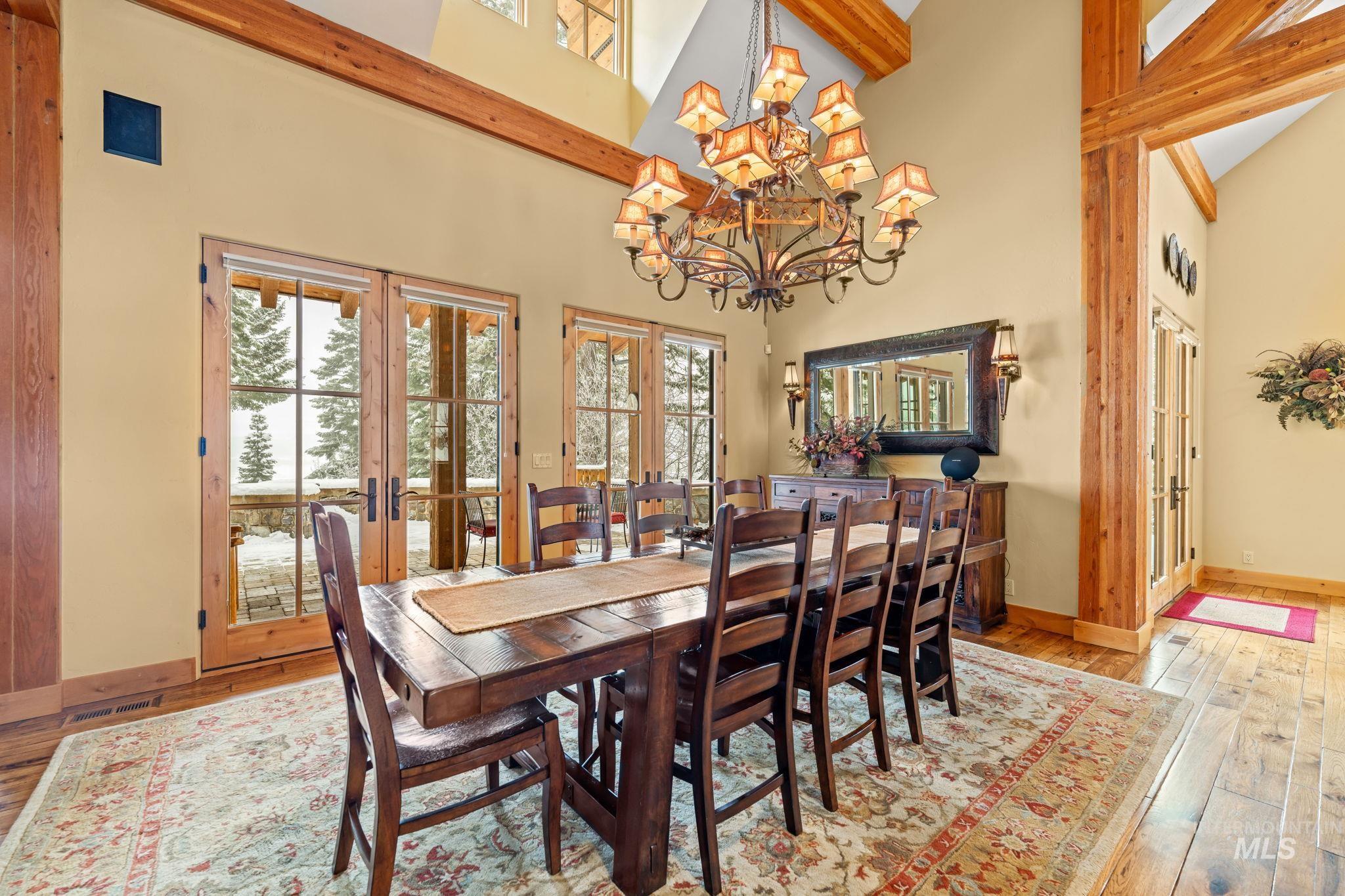 Dining space with french doors, high vaulted ceiling, hardwood / wood-style flooring, a chandelier, and healthy amount of natural light
