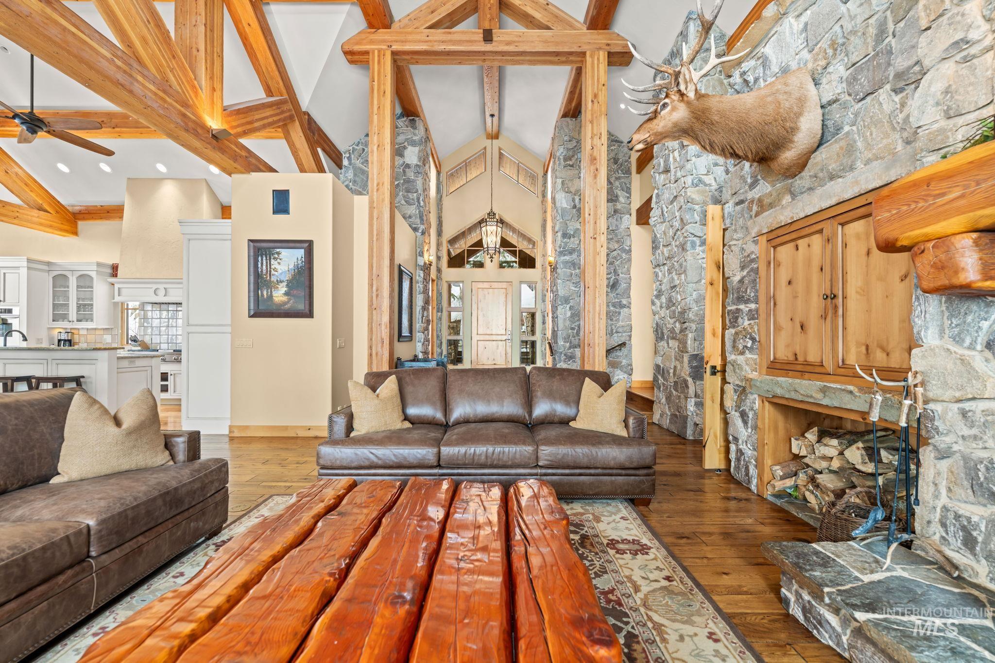 Living room with high vaulted ceiling, hardwood / wood-style flooring, beam ceiling, and ceiling fan