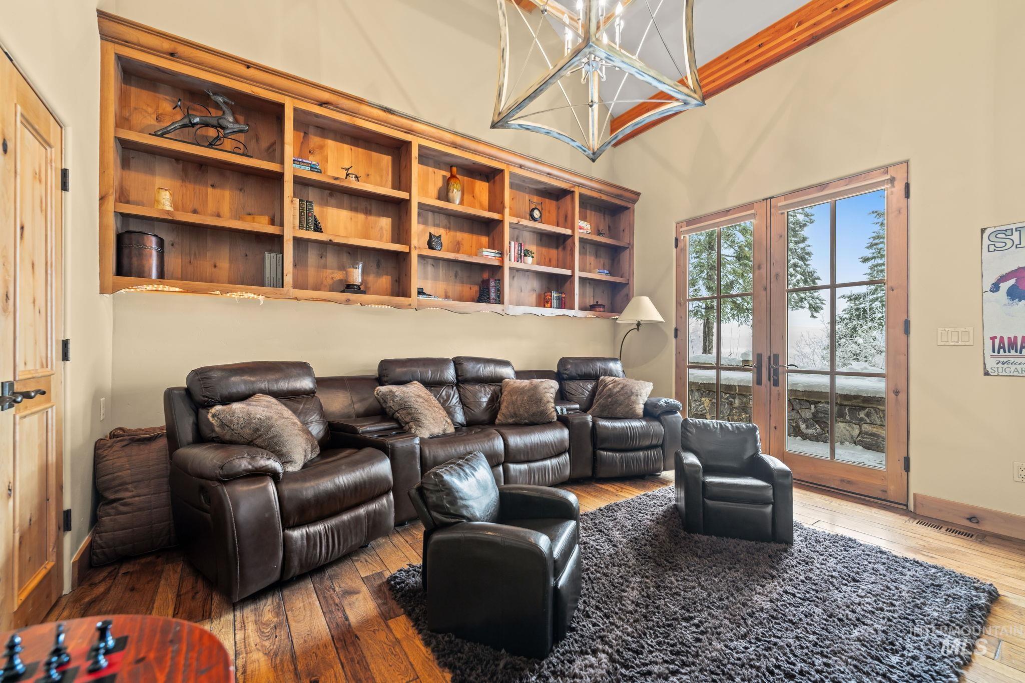 Living area with hardwood / wood-style flooring, a high ceiling, a chandelier, and french doors