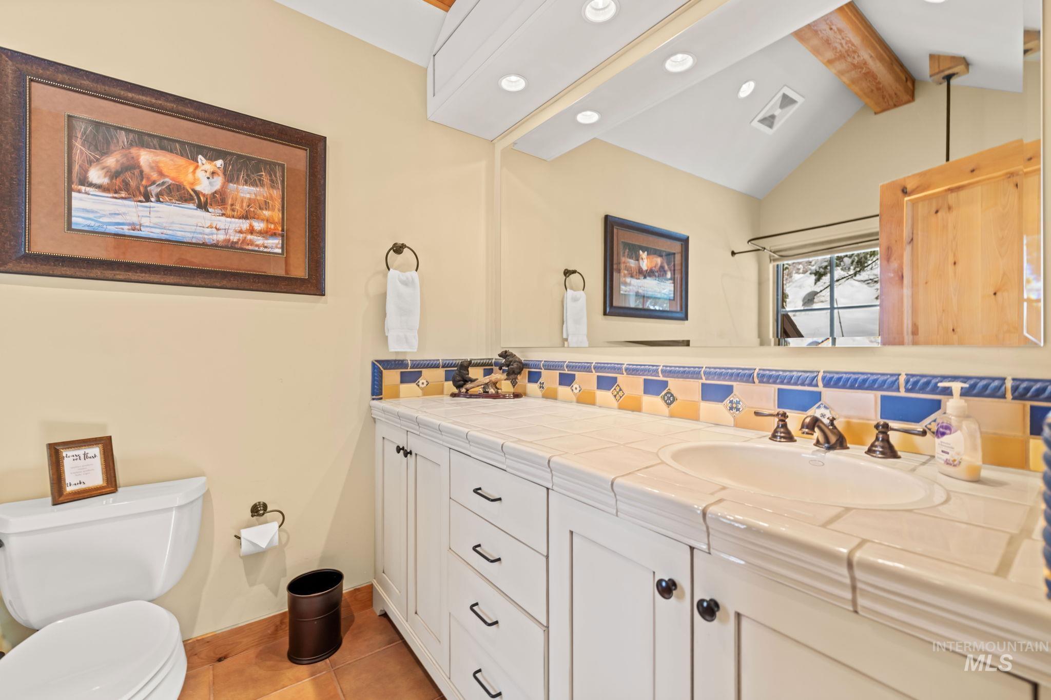 Full bath featuring tasteful backsplash, double vanity, and light tile patterned floors