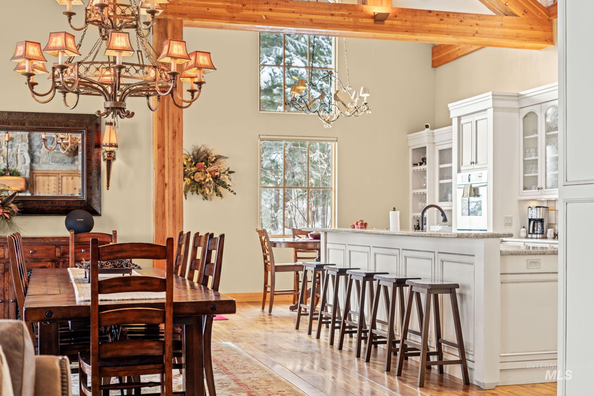 Dining room featuring a chandelier, a high ceiling, light wood-type flooring, and beam ceiling