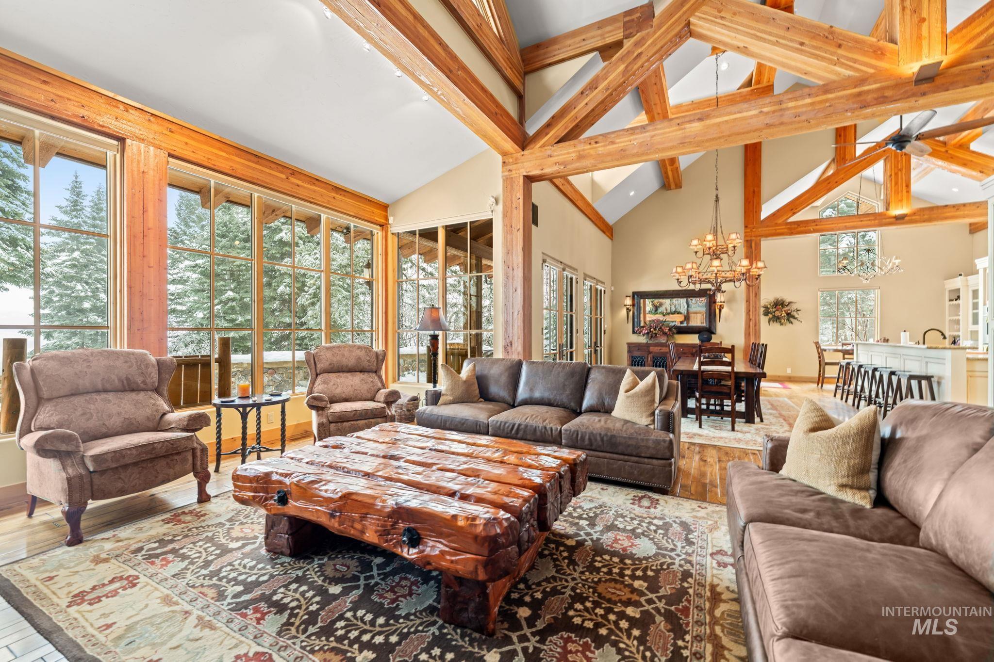 Living area with high vaulted ceiling, a chandelier, hardwood / wood-style flooring, and beamed ceiling