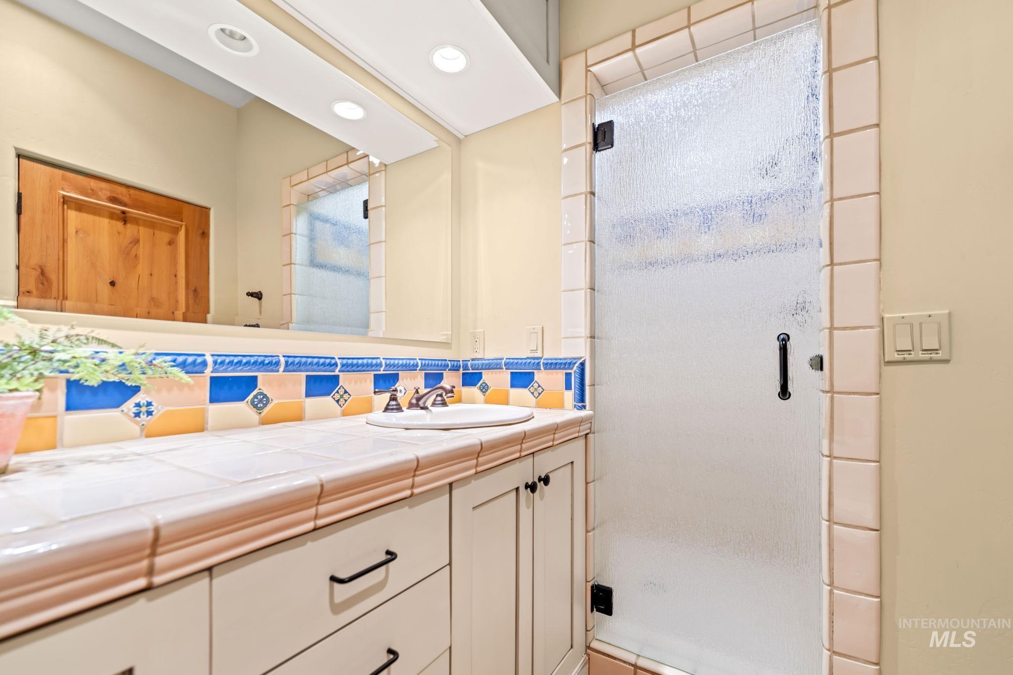 Full bath featuring a stall shower, vanity, decorative backsplash, and recessed lighting