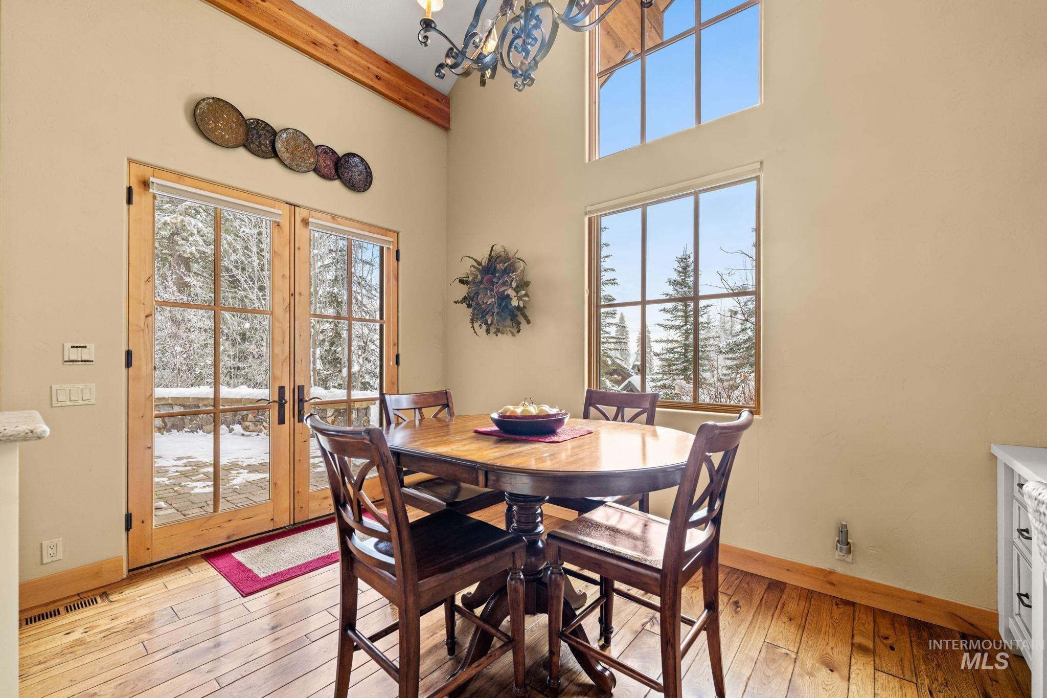 Dining space featuring a chandelier, light wood-type flooring, plenty of natural light, french doors, and a high ceiling
