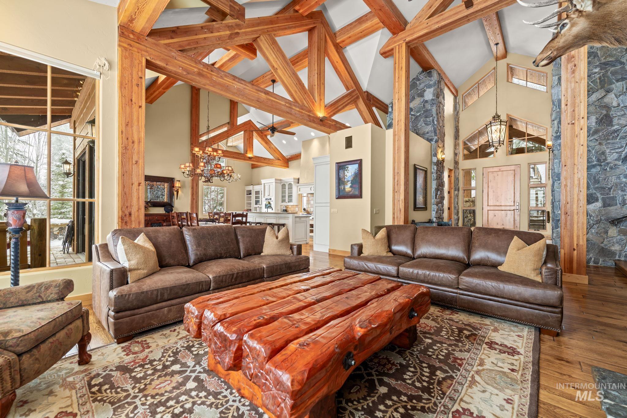 Living room featuring a chandelier, high vaulted ceiling, beam ceiling, hardwood / wood-style flooring, and ceiling fan
