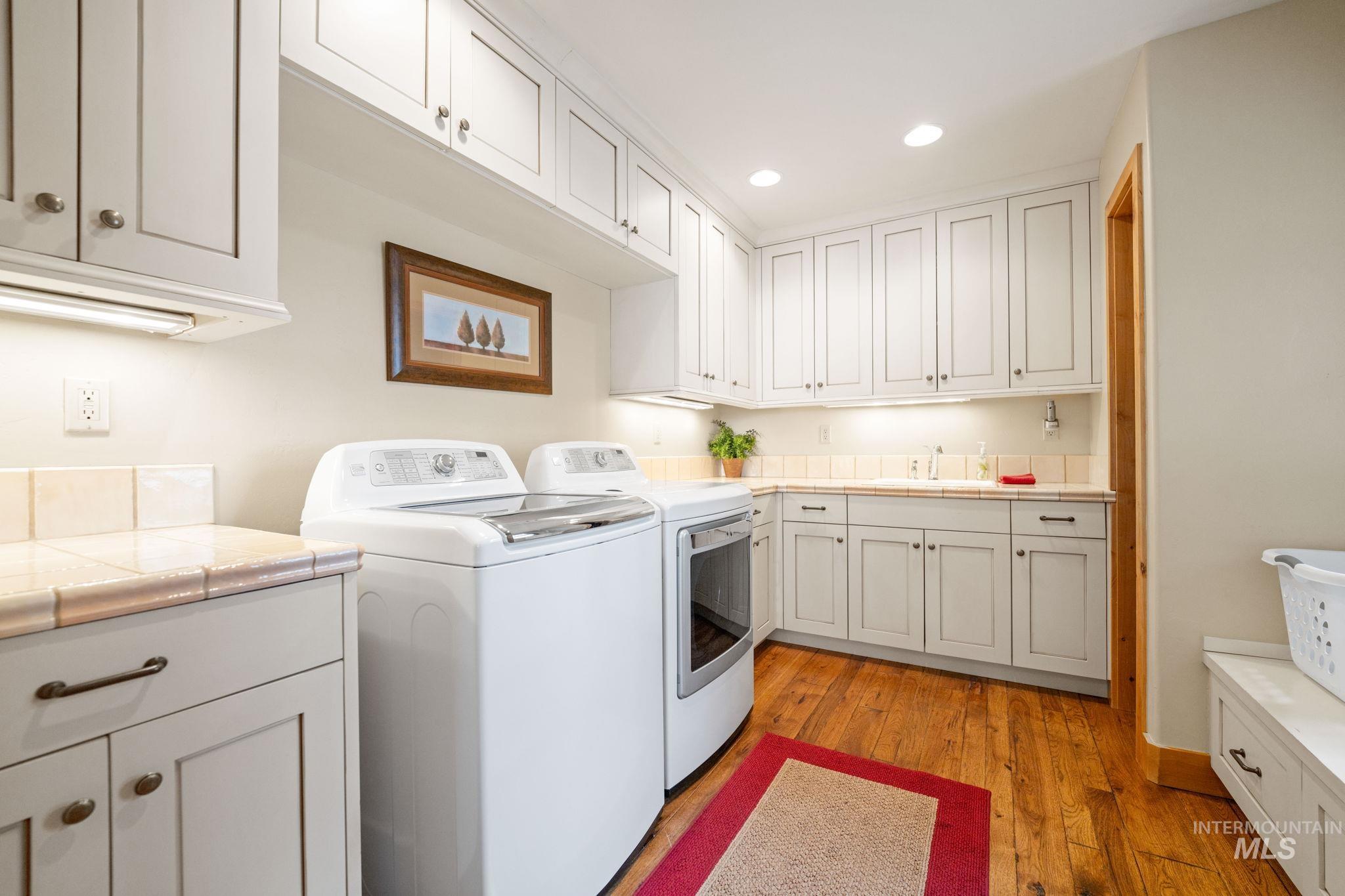 Laundry room featuring recessed lighting, cabinet space, light wood finished floors, and washer and clothes dryer