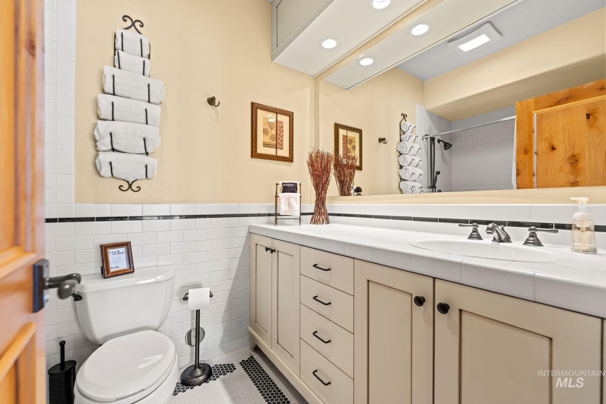 Bathroom featuring vanity, tile walls, wainscoting, and a shower with shower curtain
