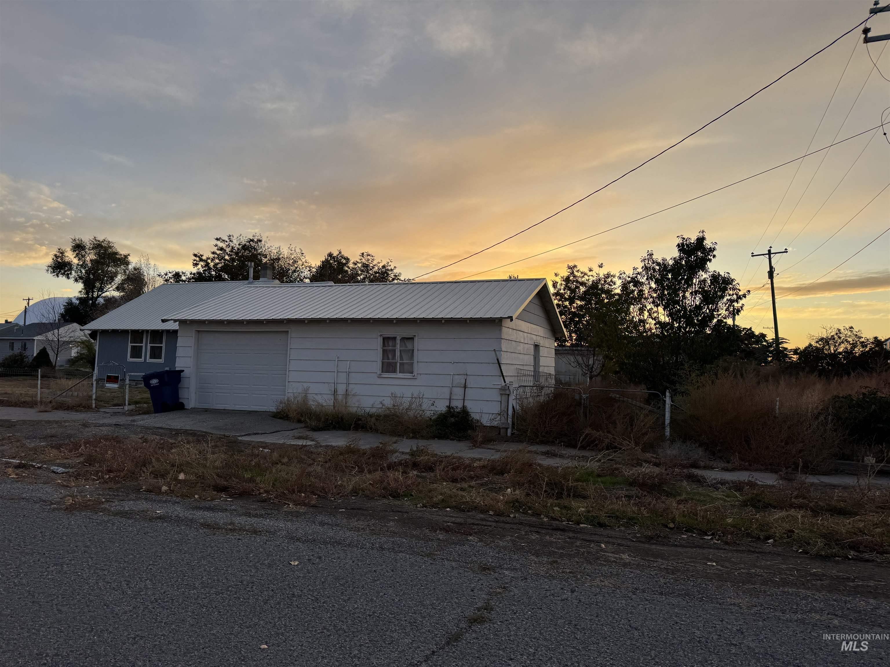 View of side of property with a metal roof, a garage, driveway, and an outdoor structure
