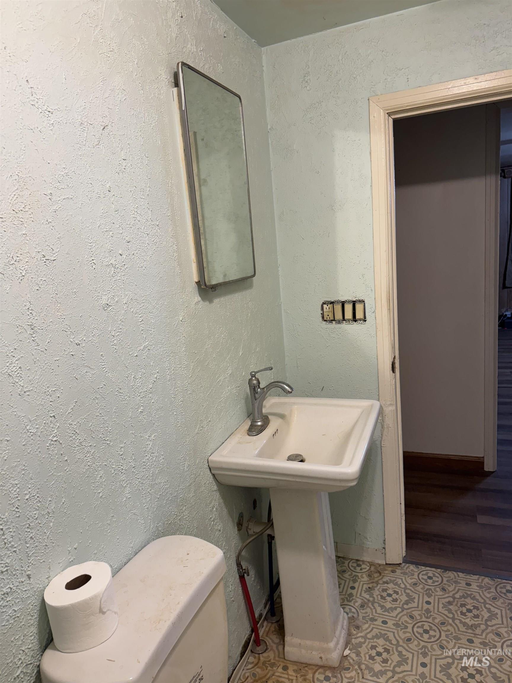 Half bathroom with a textured wall and tile patterned floors