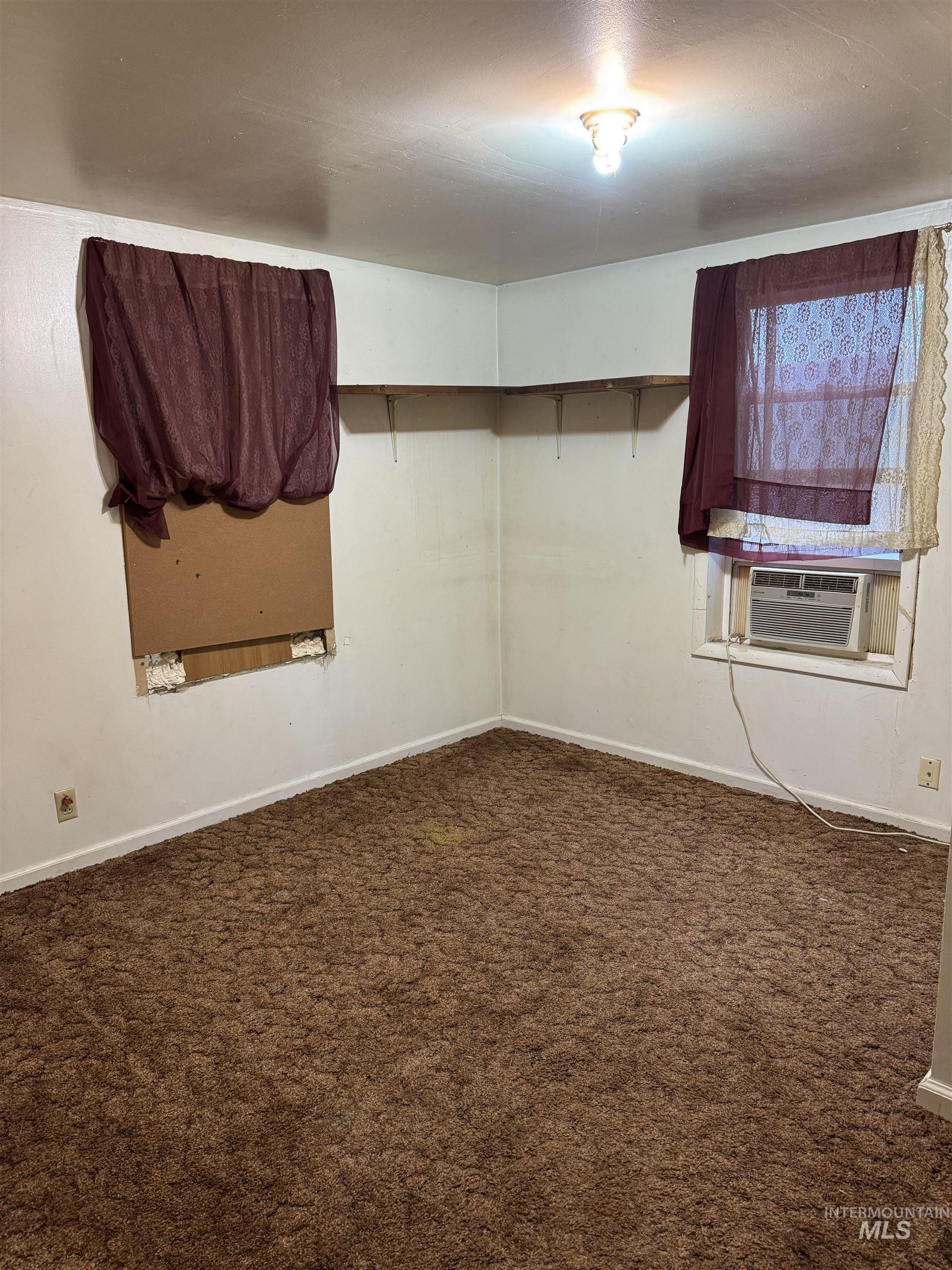 Spare room featuring dark carpet and cooling unit