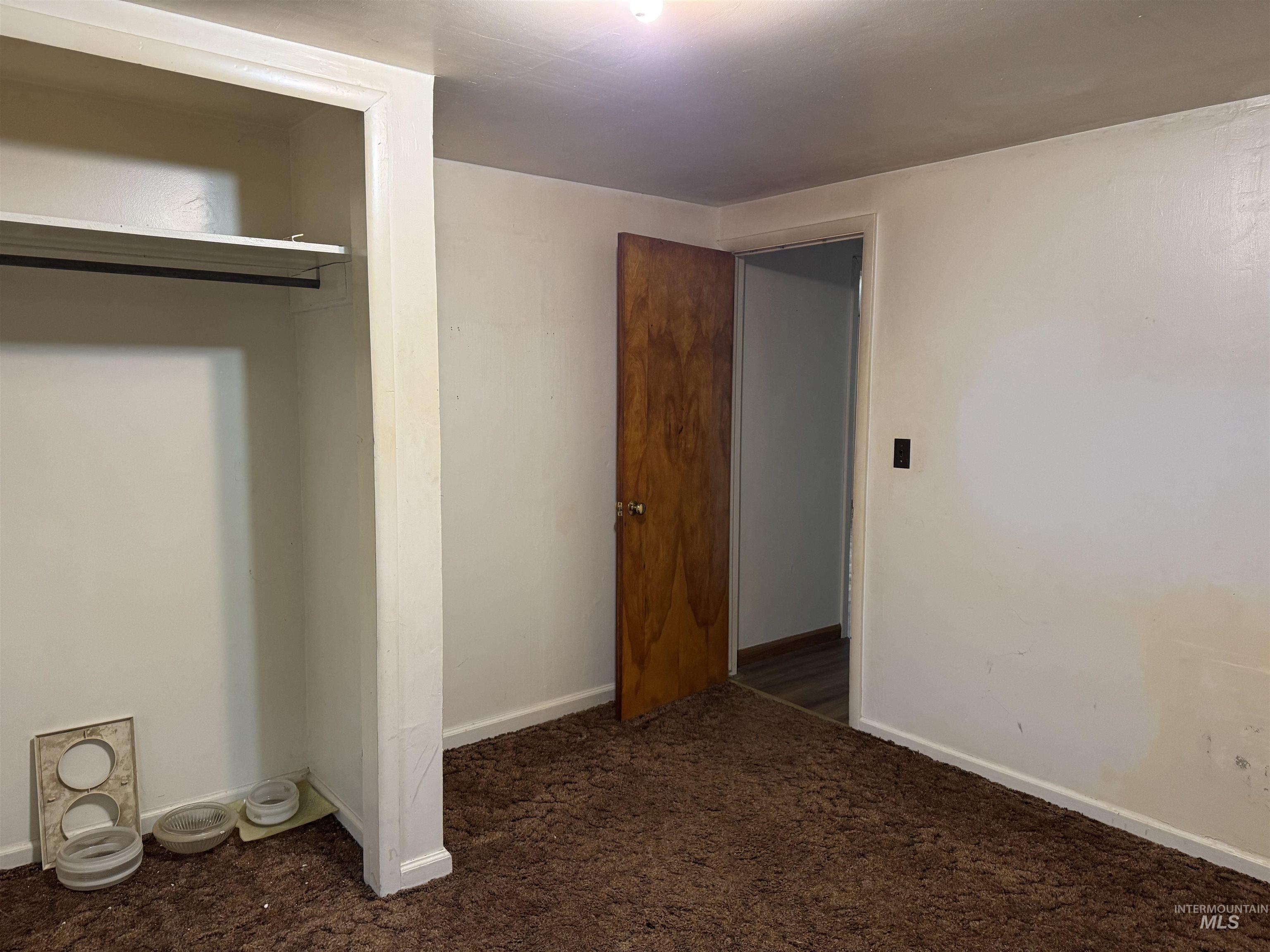 Unfurnished bedroom featuring dark carpet and baseboards