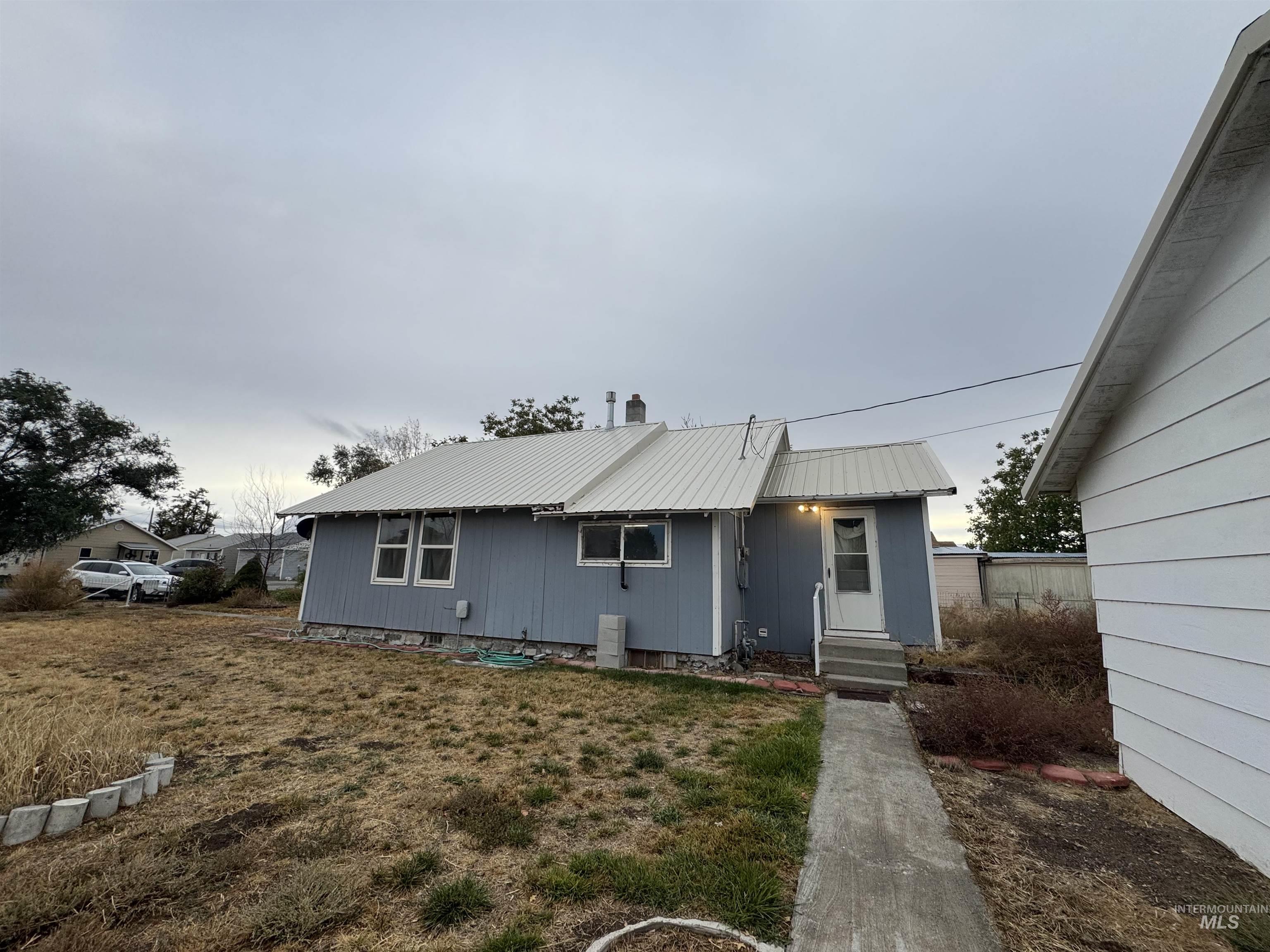 View of front of home featuring a metal roof, entry steps, a front yard, and a chimney