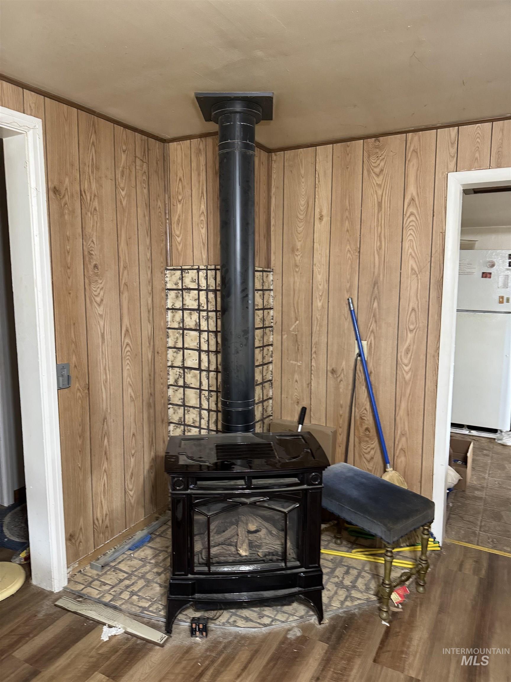 Detailed view of wooden walls, freestanding refrigerator, a wood stove, and wood finished floors