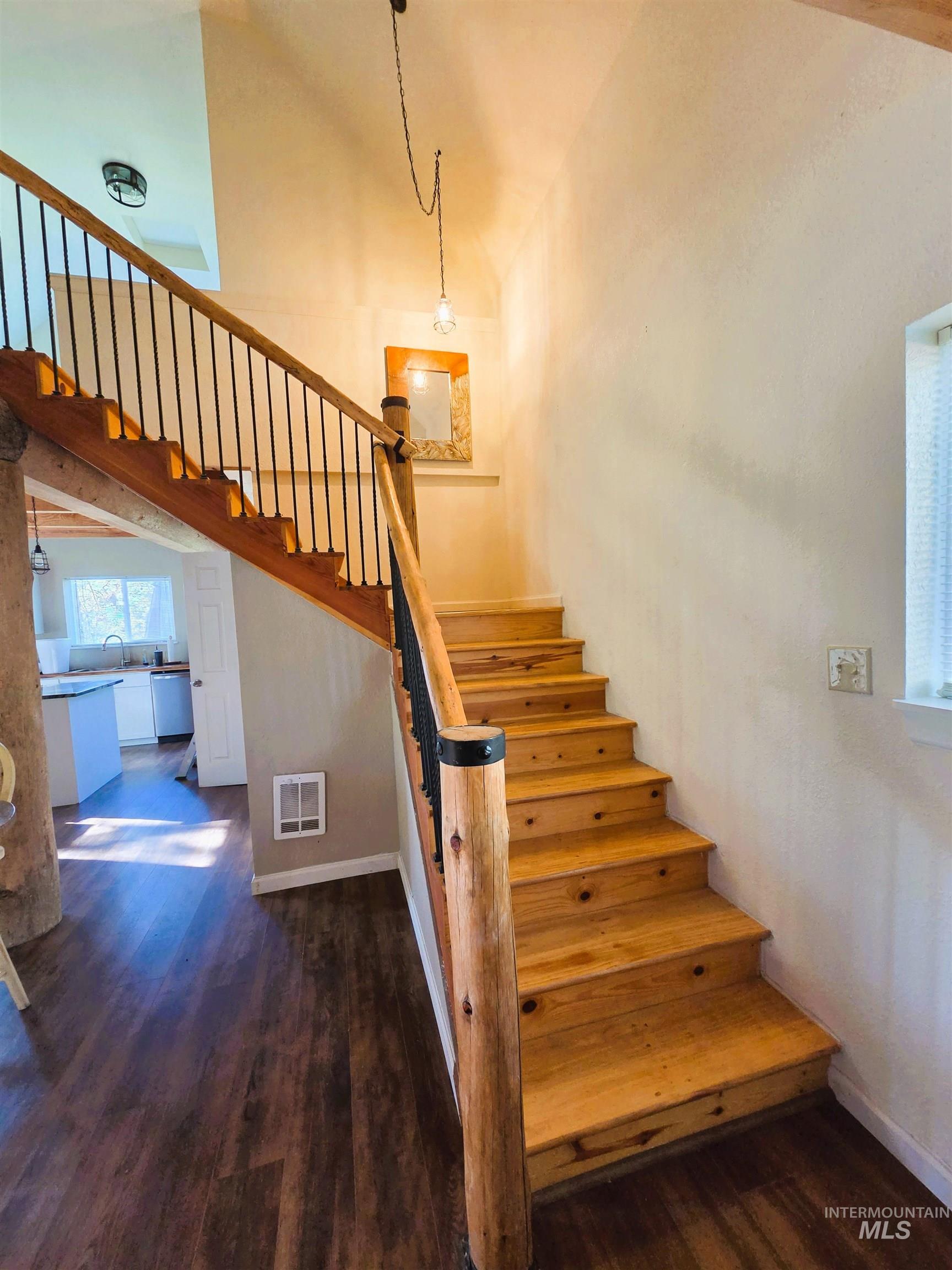 Staircase featuring natural wood treads and risers with a rustic wood newel post and black metal balusters