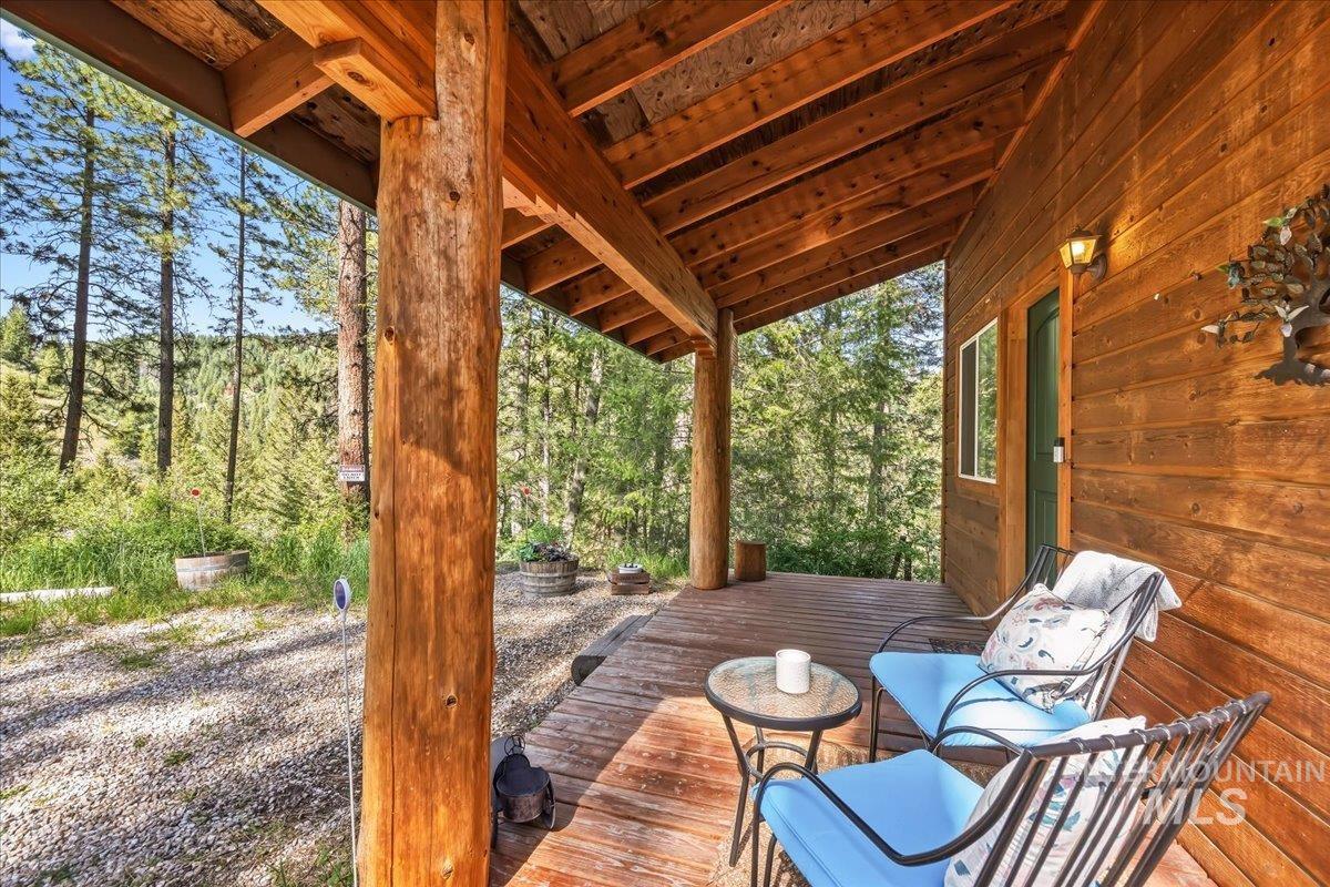 Expansive covered porch featuring natural log supports, wood-plank flooring, wood-paneled ceiling, and rustic wood-plank siding