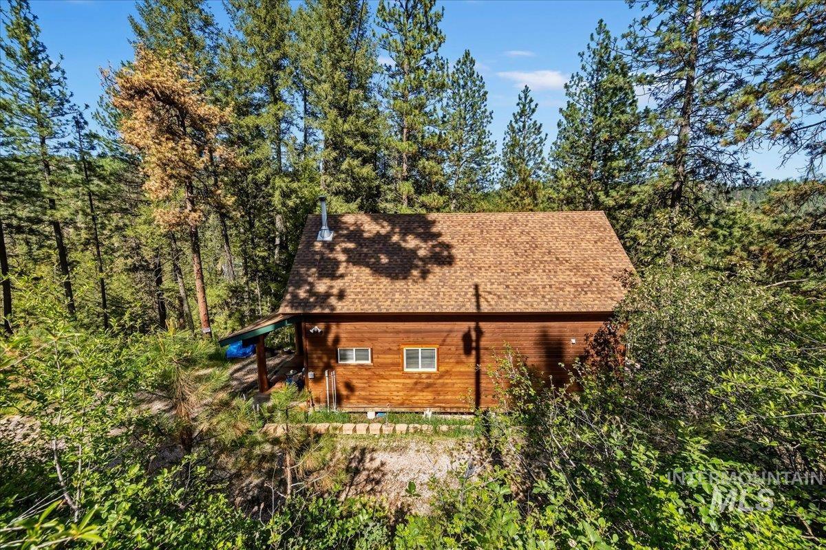 Wood-sided cabin featuring a classic A-frame roofline and a prominent chimney