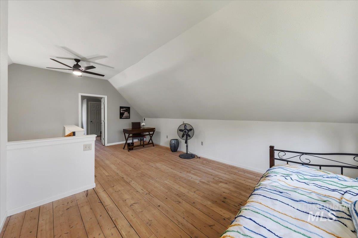 Spacious room featuring wood-finish flooring and sloped ceilings