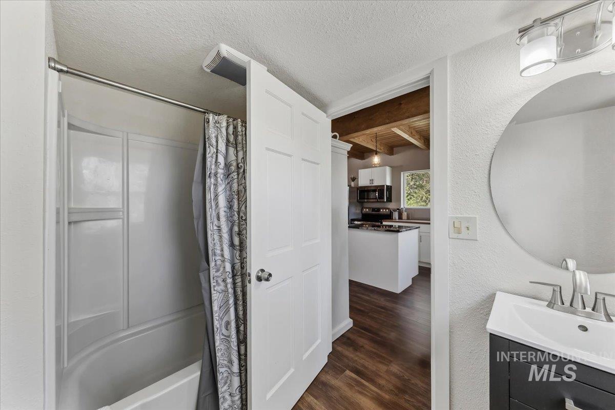 Bathroom vanity featuring a circular mirror, wall-mounted light fixture, and a single-handle faucet