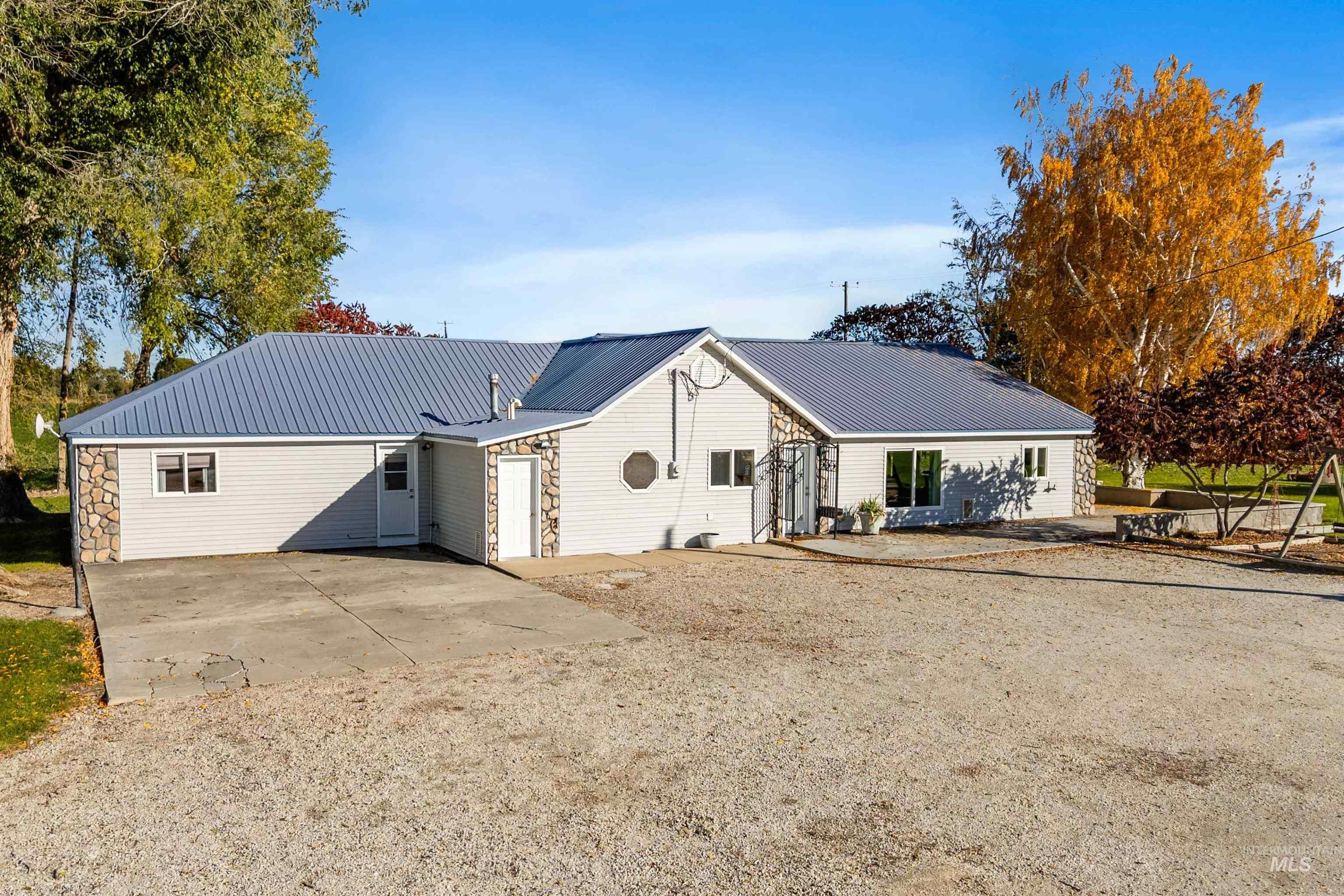 View of front of house with a metal roof and driveway